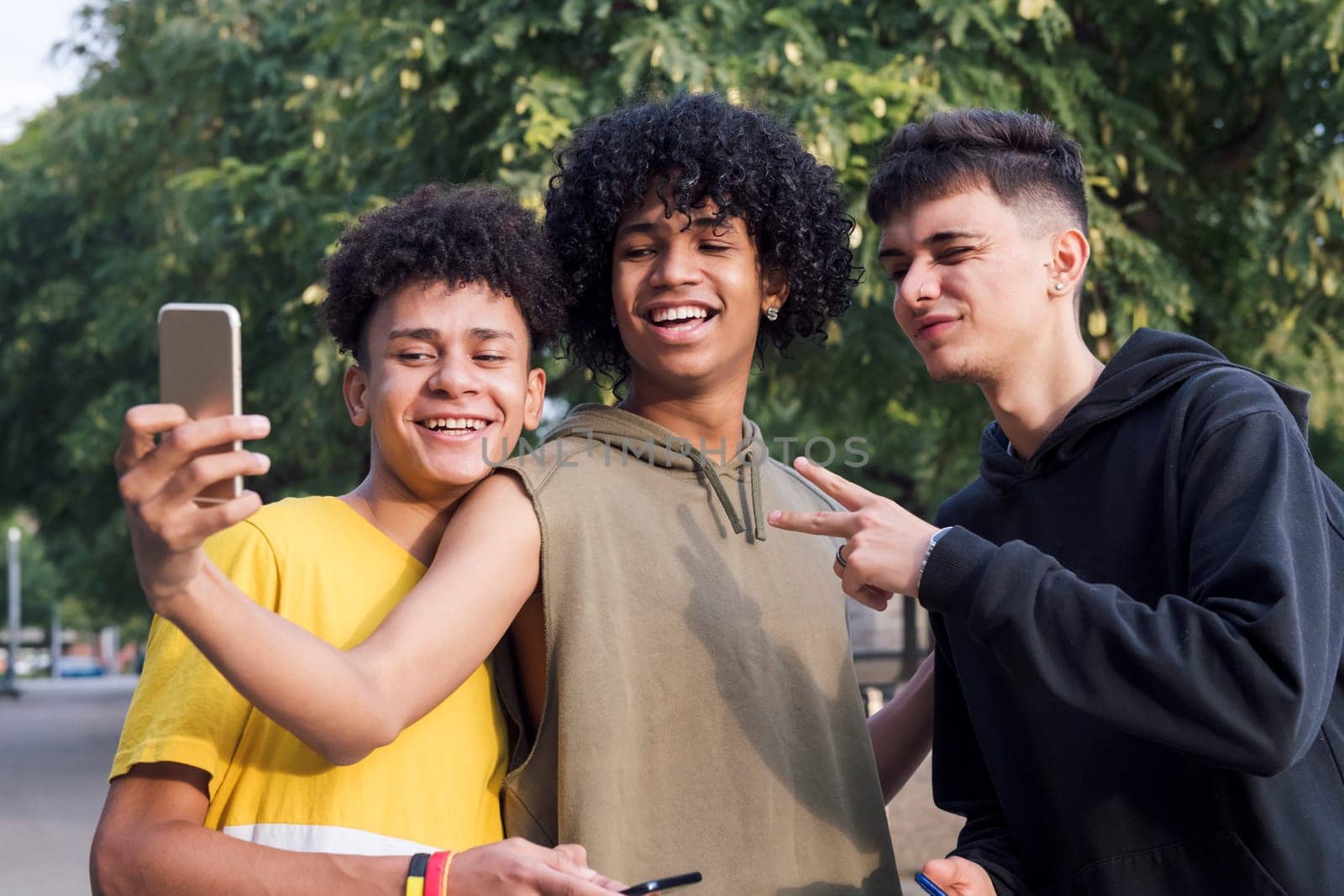 multiethnic group of three male teens smiling happy taking selfie photo with mobile phone, concept of youth lifestyle and technology of communication