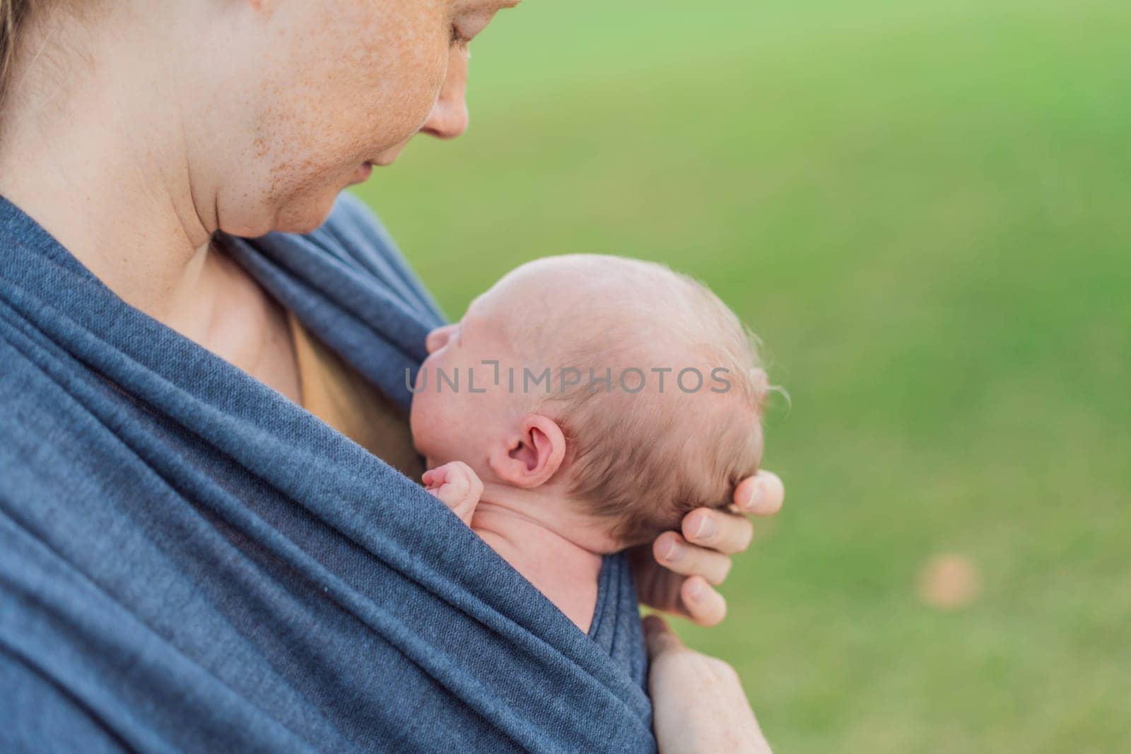 Mom walks with her newborn baby in a sling. This moment highlights the close bond between mother and child, promoting comfort, security, and the benefits of babywearing in everyday life.