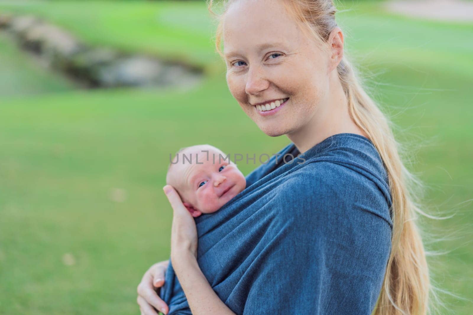 Mom walks with her newborn baby in a sling. This moment highlights the close bond between mother and child, promoting comfort, security, and the benefits of babywearing in everyday life.