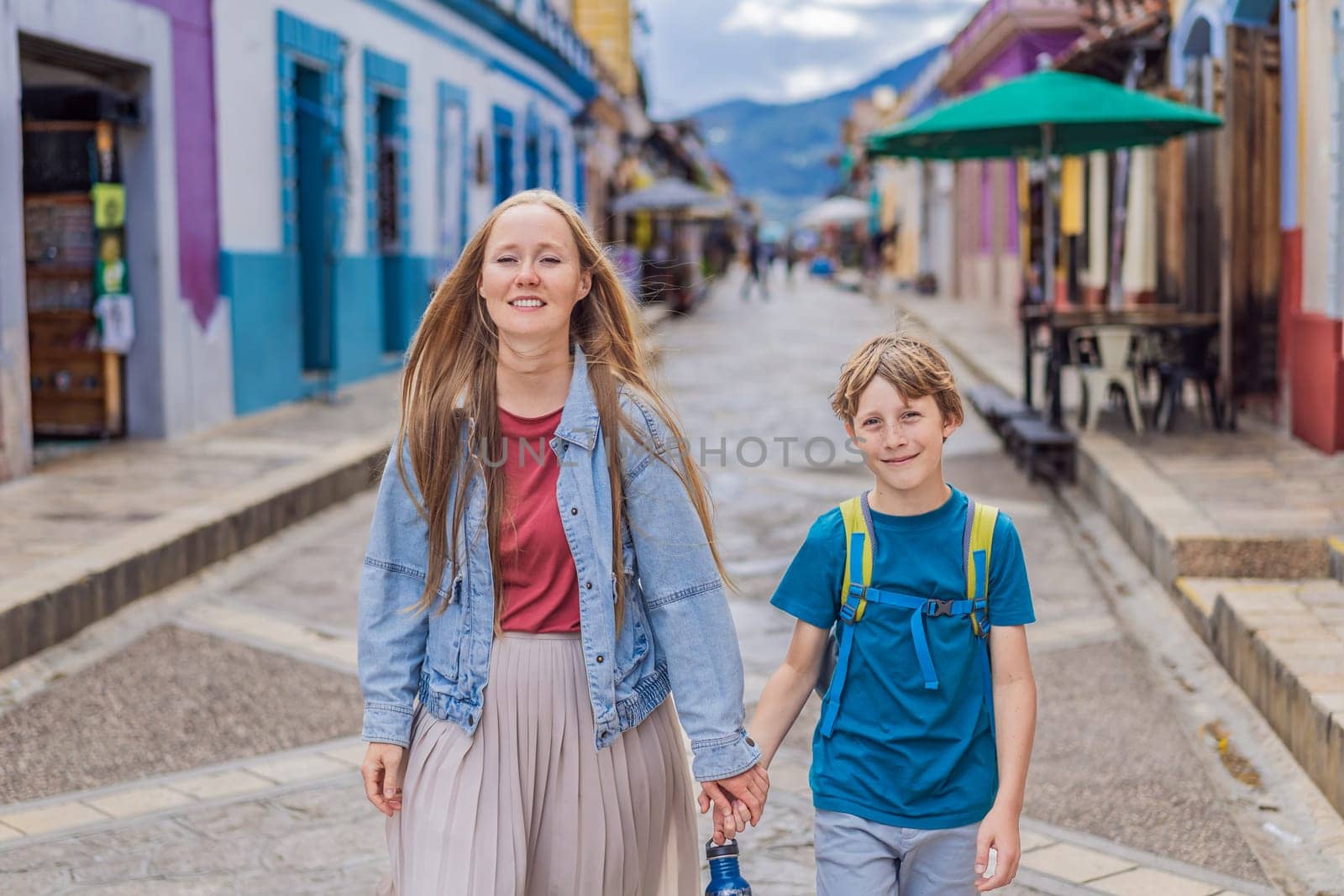 Mother and her son tourists walks through the colonial streets San Cristobal de las Casas, Mexico. Cultural exploration, architecture, and travel experience concept.