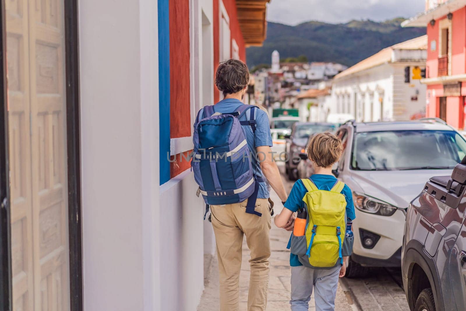 Father and and his two sons, a teenager and a baby tourists walks through the colonial streets San Cristobal de las Casas, Mexico. Cultural exploration, architecture, and travel experience concept.