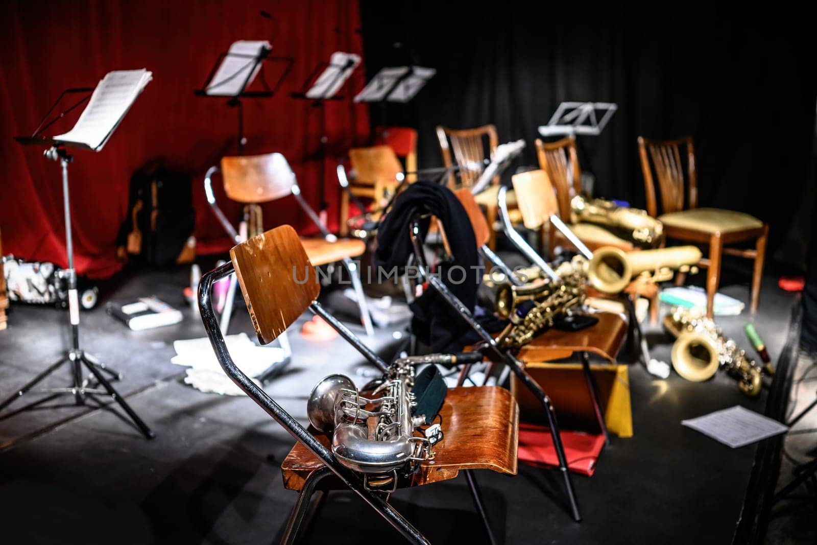 Concert hall stage and saxophones lying on chairs after jazz music live performance. Musical instruments for acoustic show