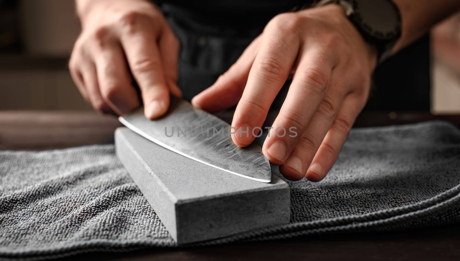 Man sharpening a knife with whetstone, closeup view