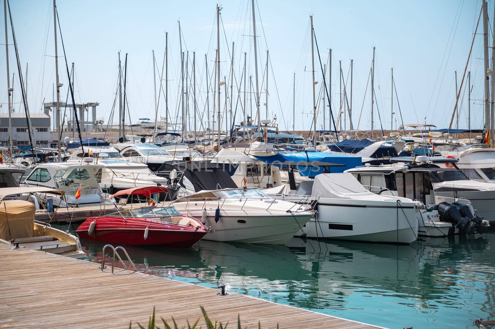 A bustling marina with numerous boats and yachts docked in calm waters. Clear skies and serene atmosphere idealize this coastal scene, capturing the essence of nautical life.
