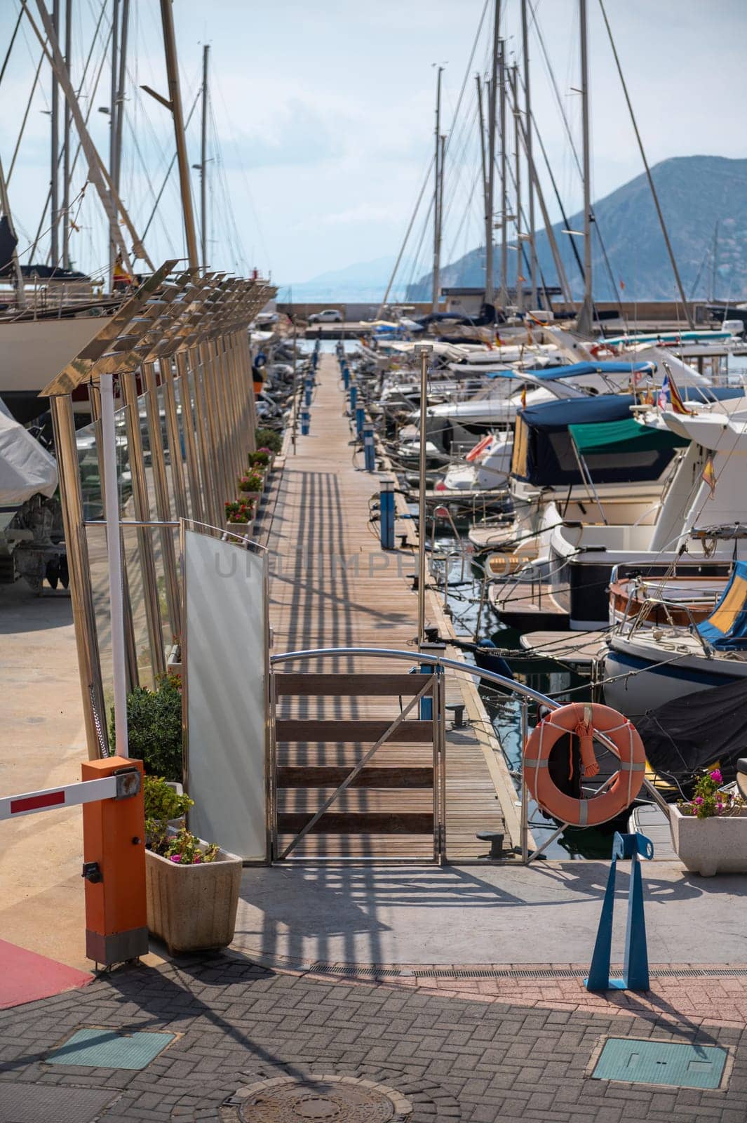 A picturesque marina showcasing numerous yachts and boats, tied to a wooden dock under a clear blue sky, embodying tranquility and nautical adventure.