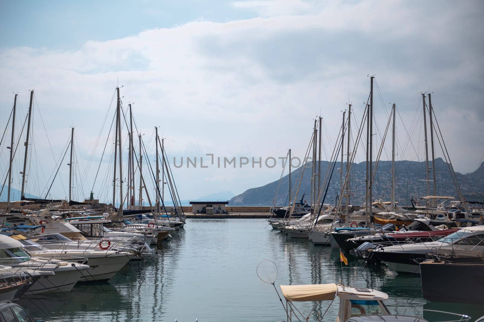 A peaceful marina scene featuring numerous yachts and sailboats, with calm waters and a mountainous backdrop, conveying a sense of leisure and escape.