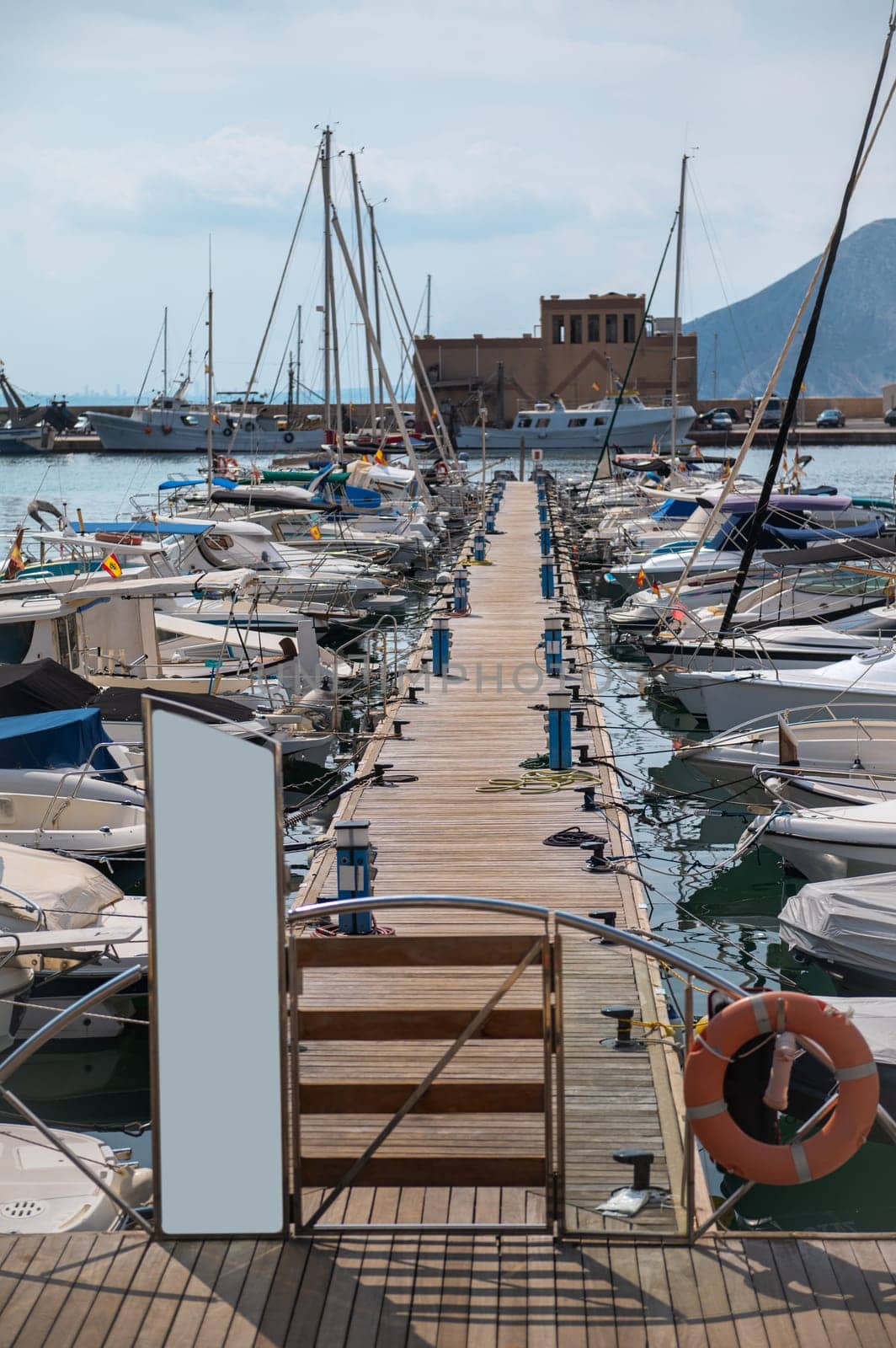 Scenic view of a marina with numerous boats docked along a wooden pier, under a tranquil sky. A perfect setting for sailing enthusiasts.