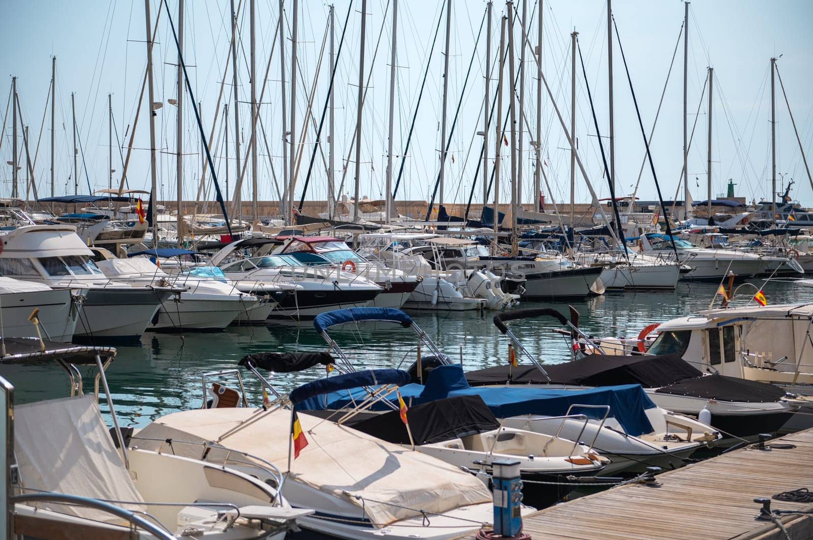 A picturesque view of a bustling marina filled with yachts and sailboats neatly docked, reflecting the serene ambiance of the waterside setting.