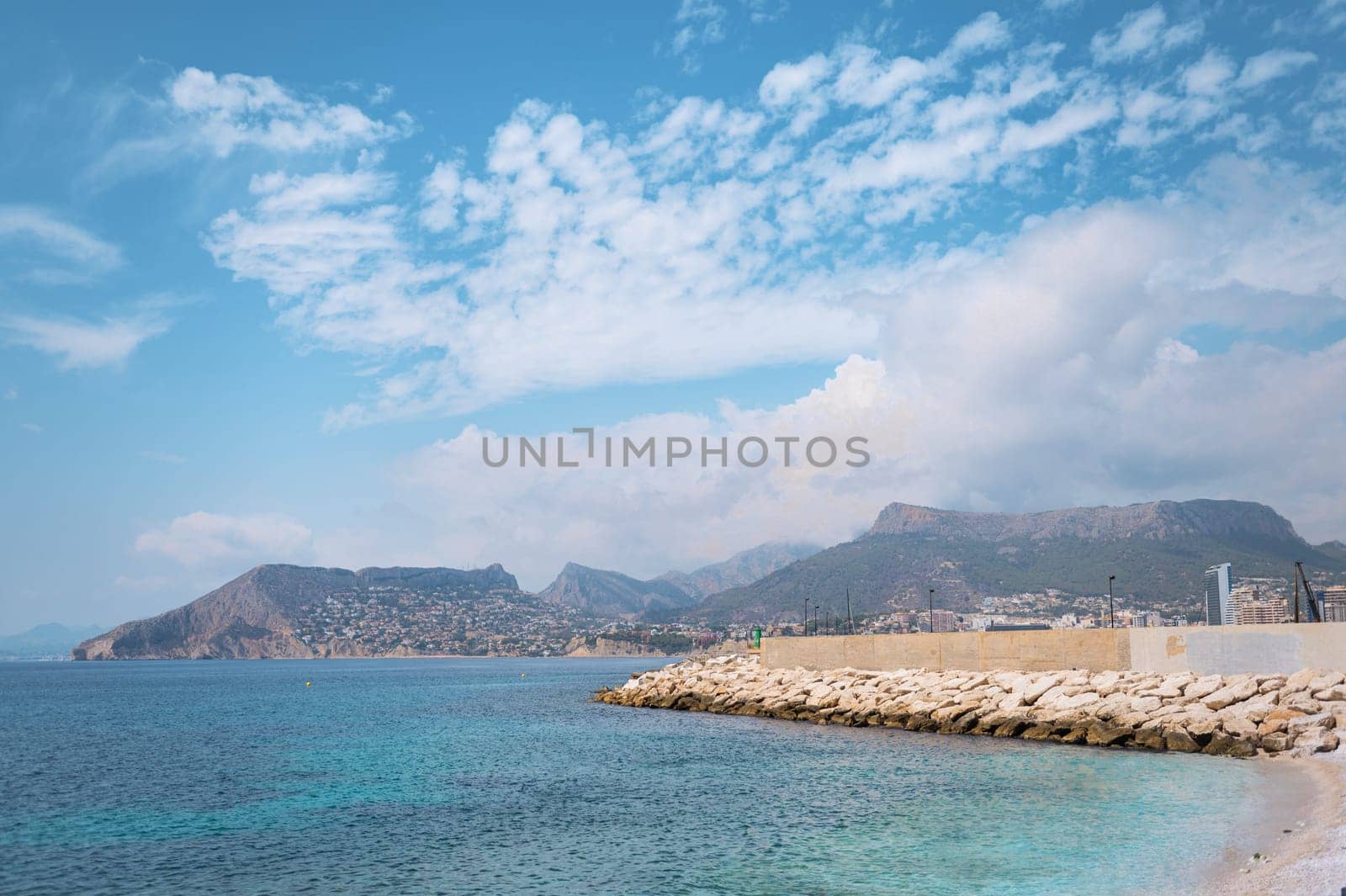 Beautiful coastal landscape featuring mountains, clear blue skies, and tranquil waters. Ideal representation of natural beauty and serene sea vibes.