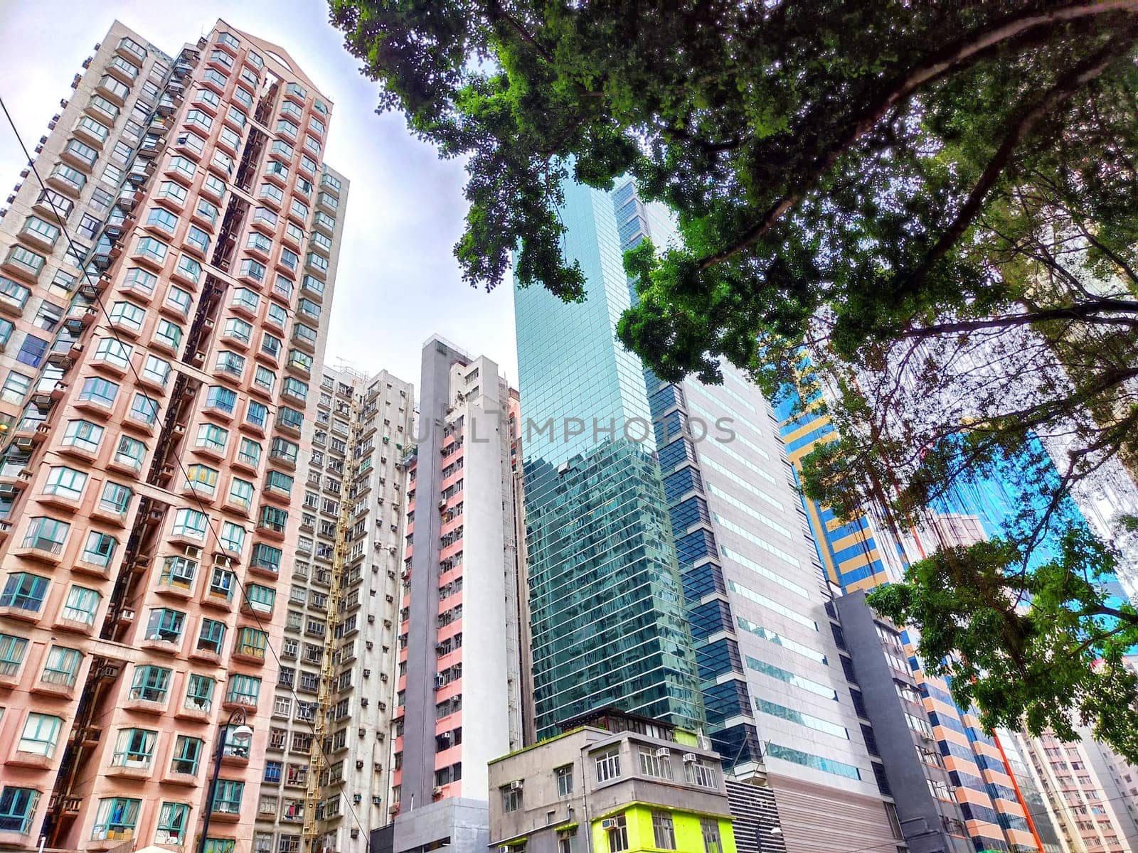 Towers dominate the skyline with a mix of modern and classic architecture under a cloudy sky.