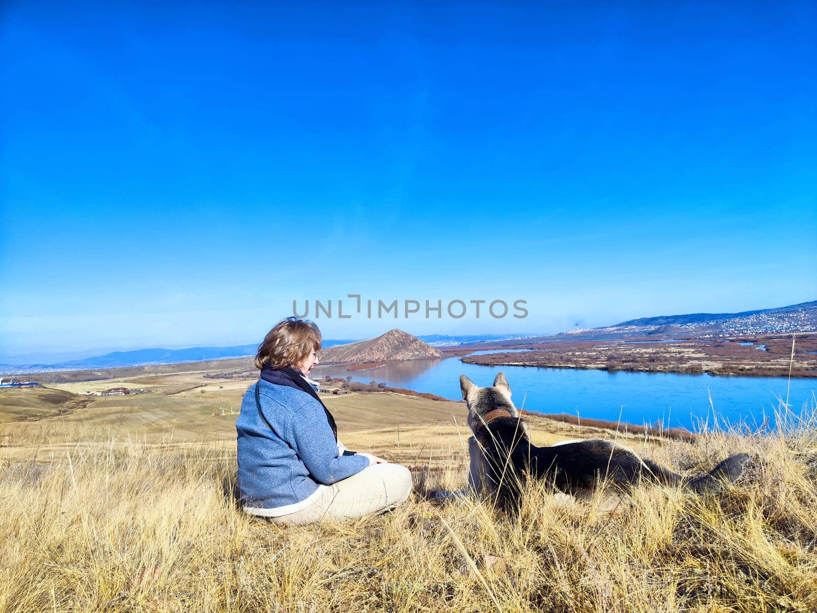 A woman and her German Shepherd enjoy a hike overlooking a picturesque lake on a clear sunny spring morning