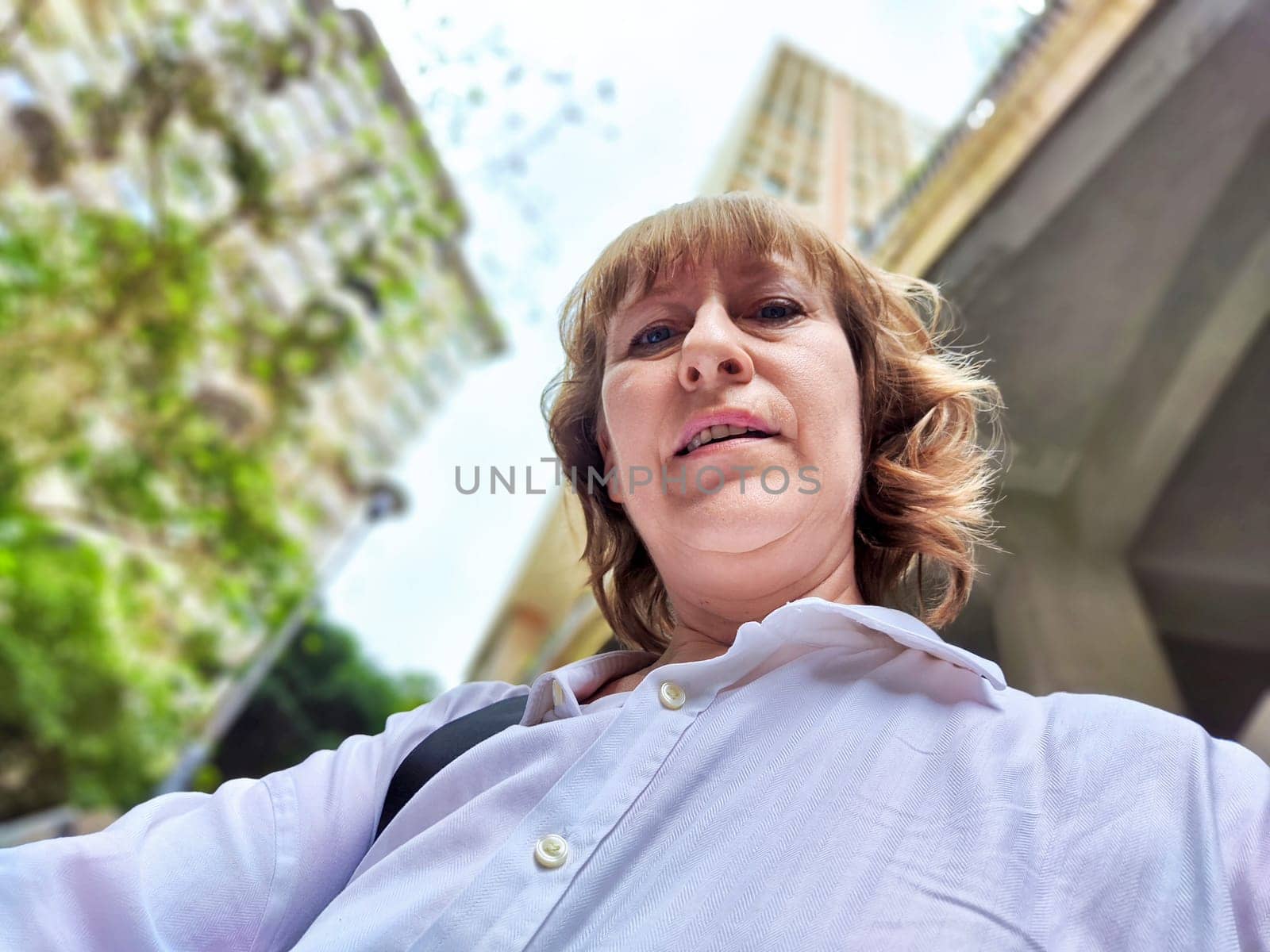 A woman captures her excitement while touring a unique, contemporary building during her travels. The adventures of middle-aged female tourist on a trip
