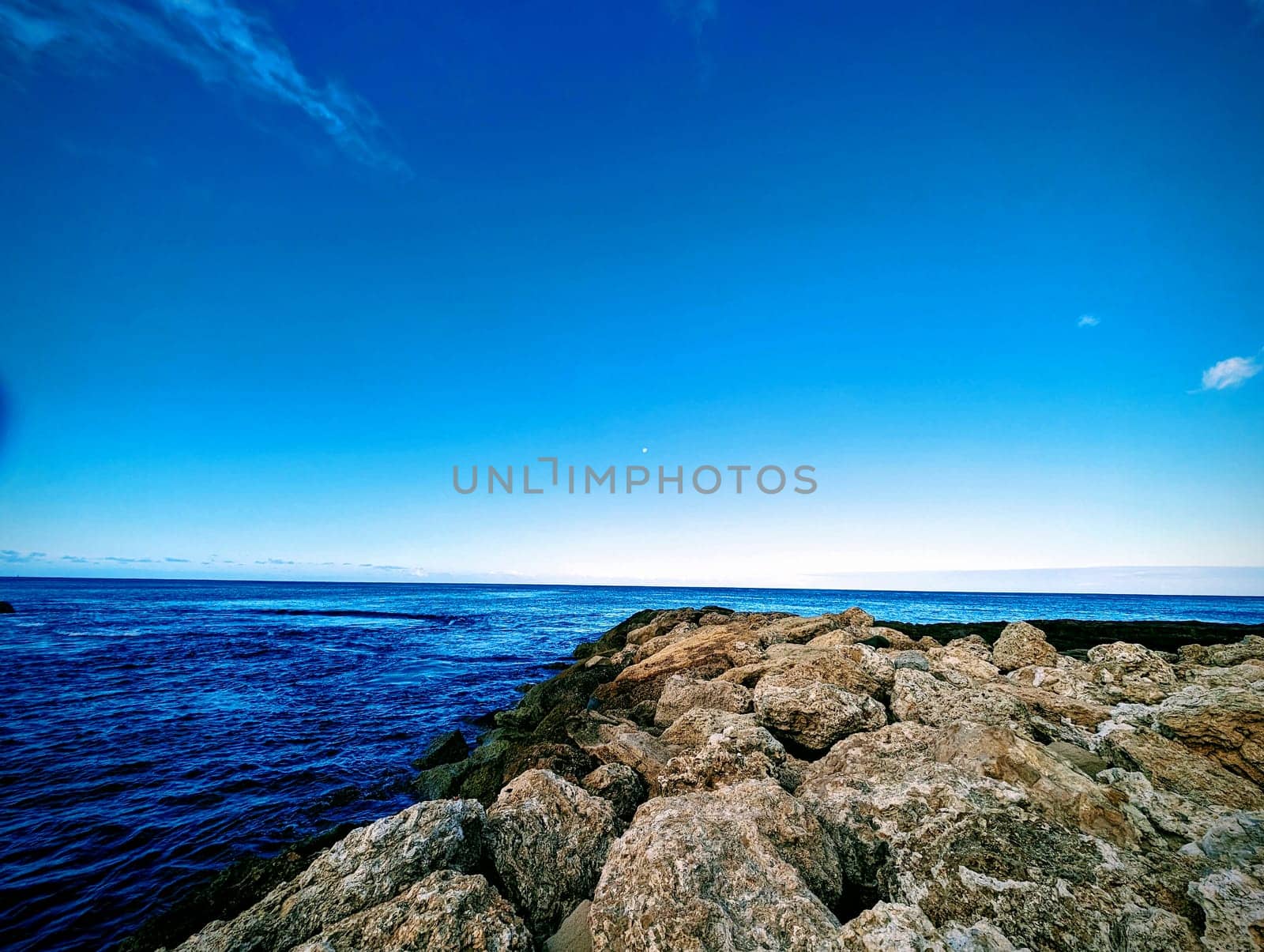 Gentle waves lapping against the rocks at Ko Olina Lagoon under a clear sky, creating a serene atmosphere perfect for relaxation.