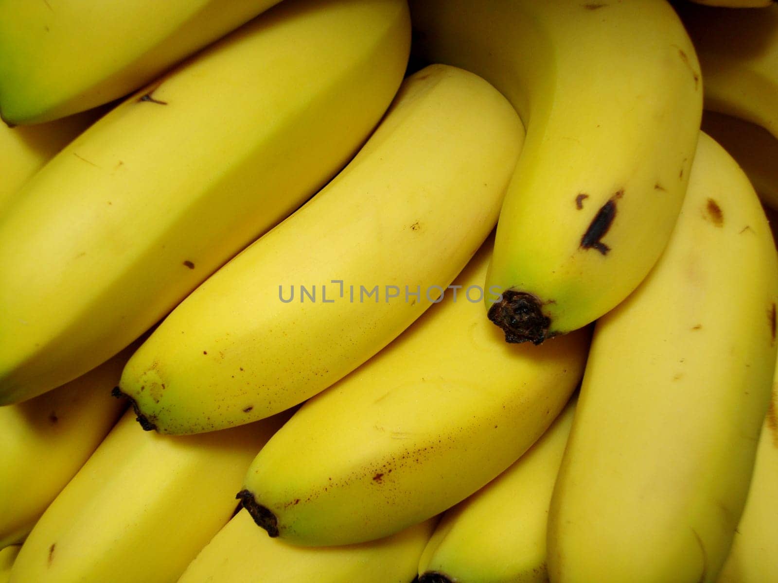 A cluster of ripe yellow bananas is neatly arranged in a grocery store, highlighting their appealing color and freshness for shoppers.