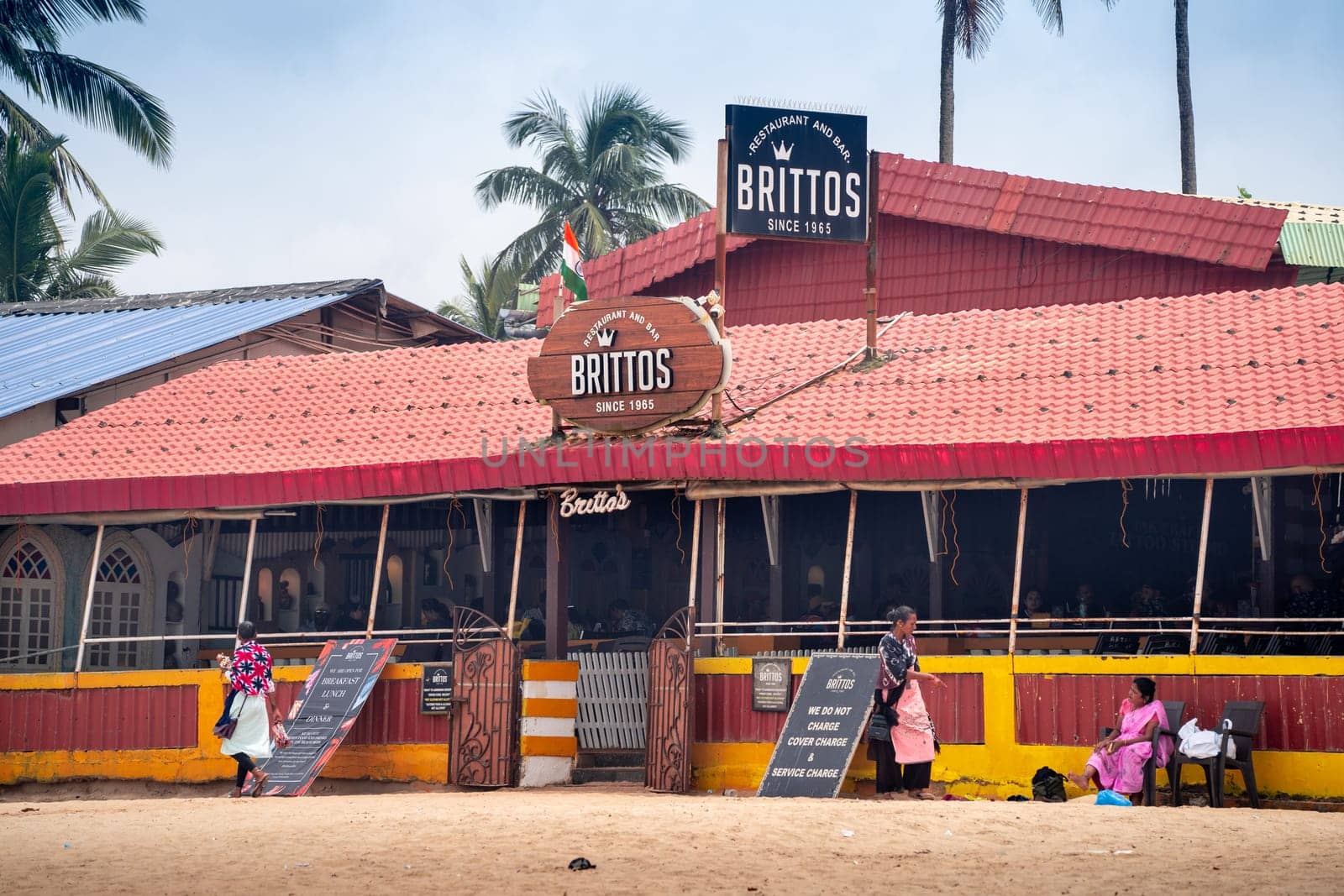 Goa, India - 16th Aug 2024: wide angle shot showing famous bar shack Brittos on baga calangute beach with red tiled roof, people roaming around this popular tourist spot