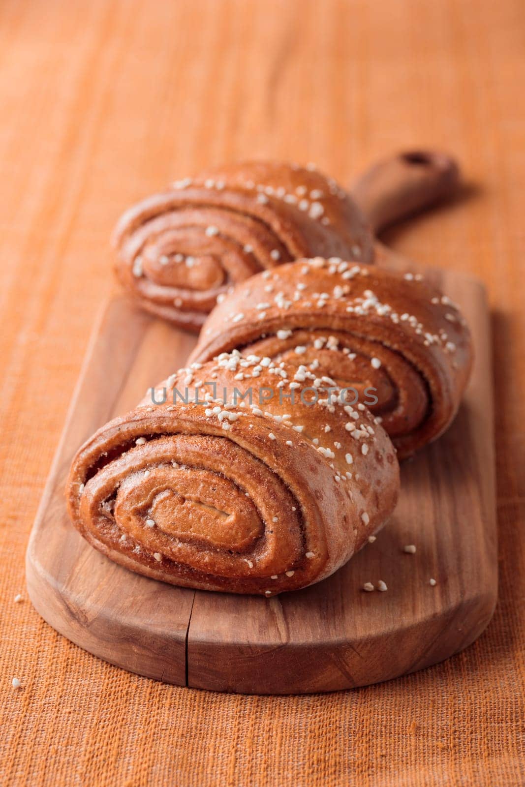 Korvapuusti, traditional finnish cinnamon and cardamom rolls, fresh baked buns on the wooden board, sweet dessert Sweden and Finland, horizontal banner with copy space