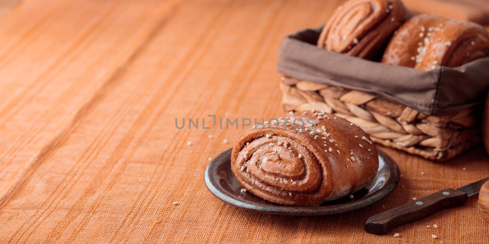 Korvapuusti, traditional finnish cinnamon and cardamom rolls, fresh baked buns on the plate, sweet dessert Sweden and Finland, horizontal banner with copy space