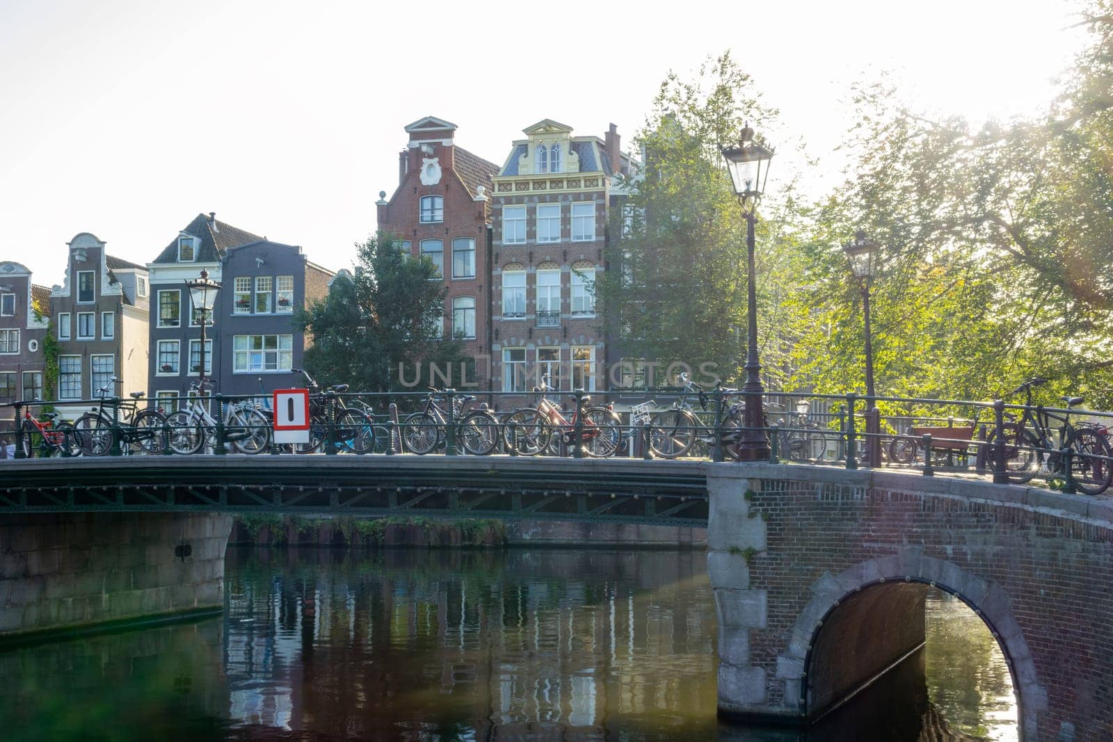 Netherlands. Sunny summer morning on the Amsterdam canal. Lots of bicycles on the bridge and traditional buildings