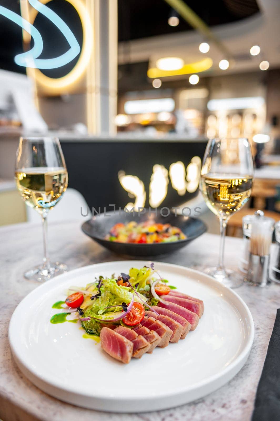 Tuna tataki salad with lettuce, cherry tomatoes and avocado on a marble table in a restaurant. High quality photo