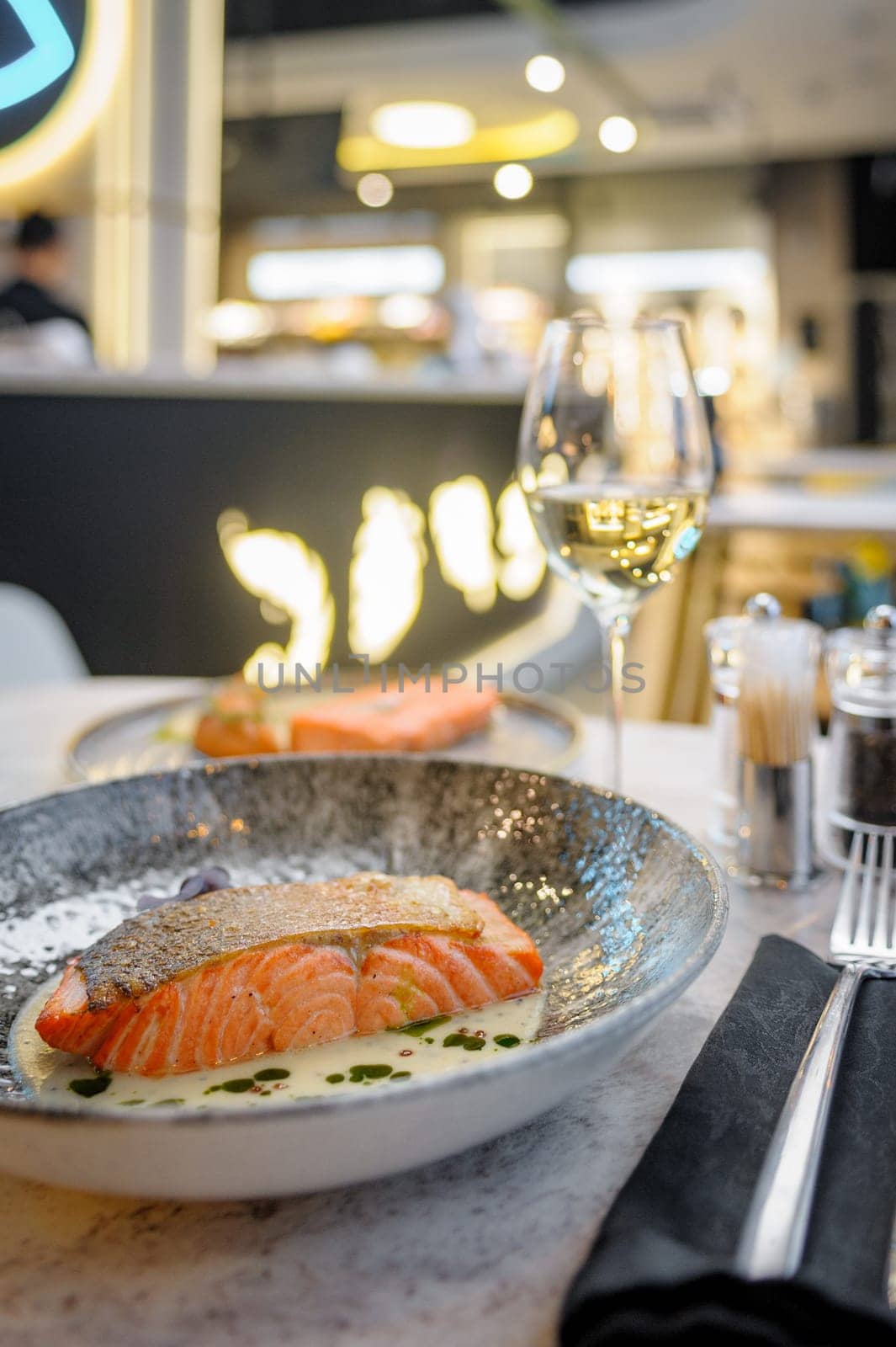 Salmon fillet in cream sauce with herbs on a marble table in a restaurant. High quality photo