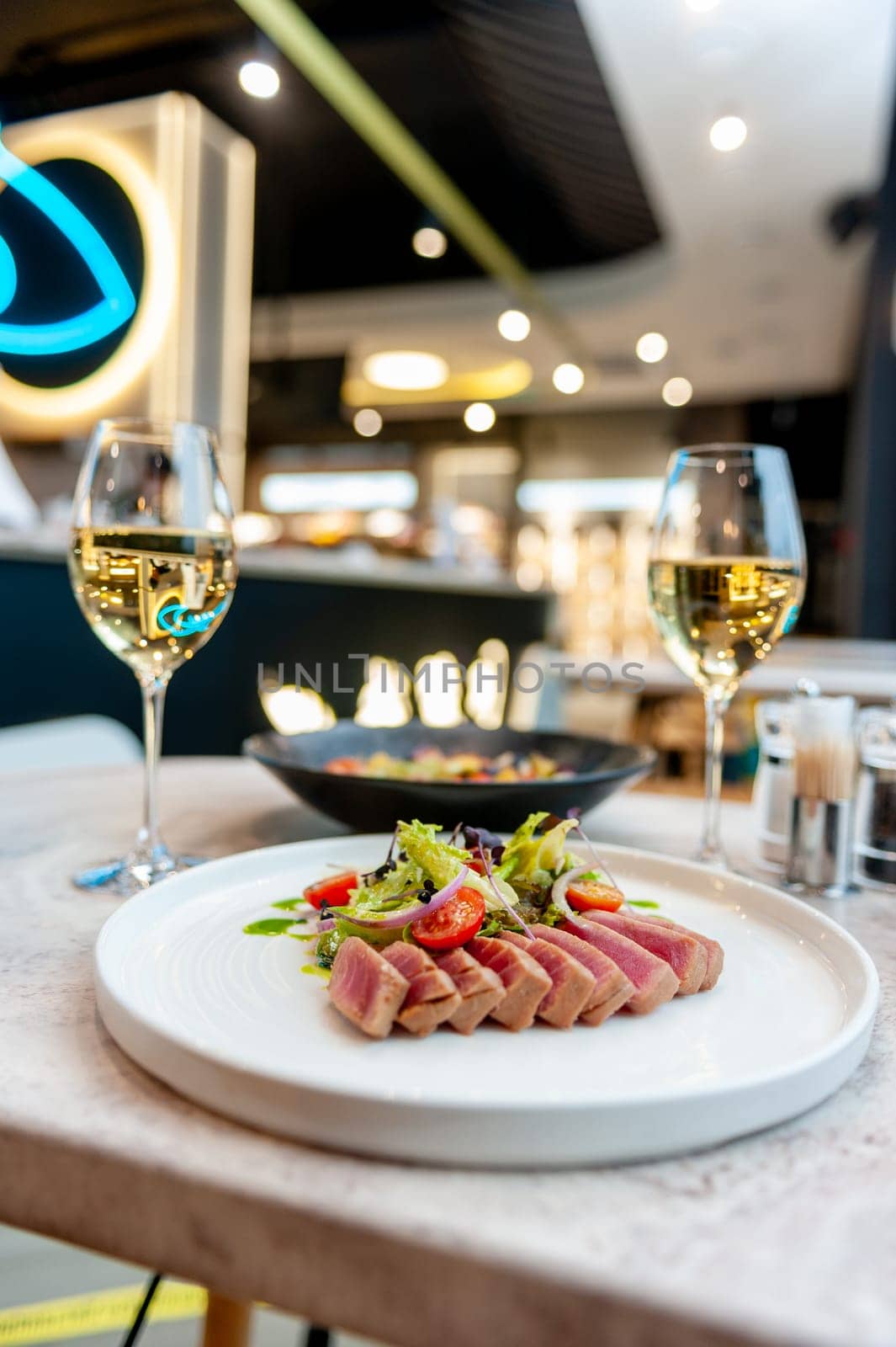 Tuna tataki salad with lettuce, cherry tomatoes and avocado on a marble table in a restaurant. High quality photo