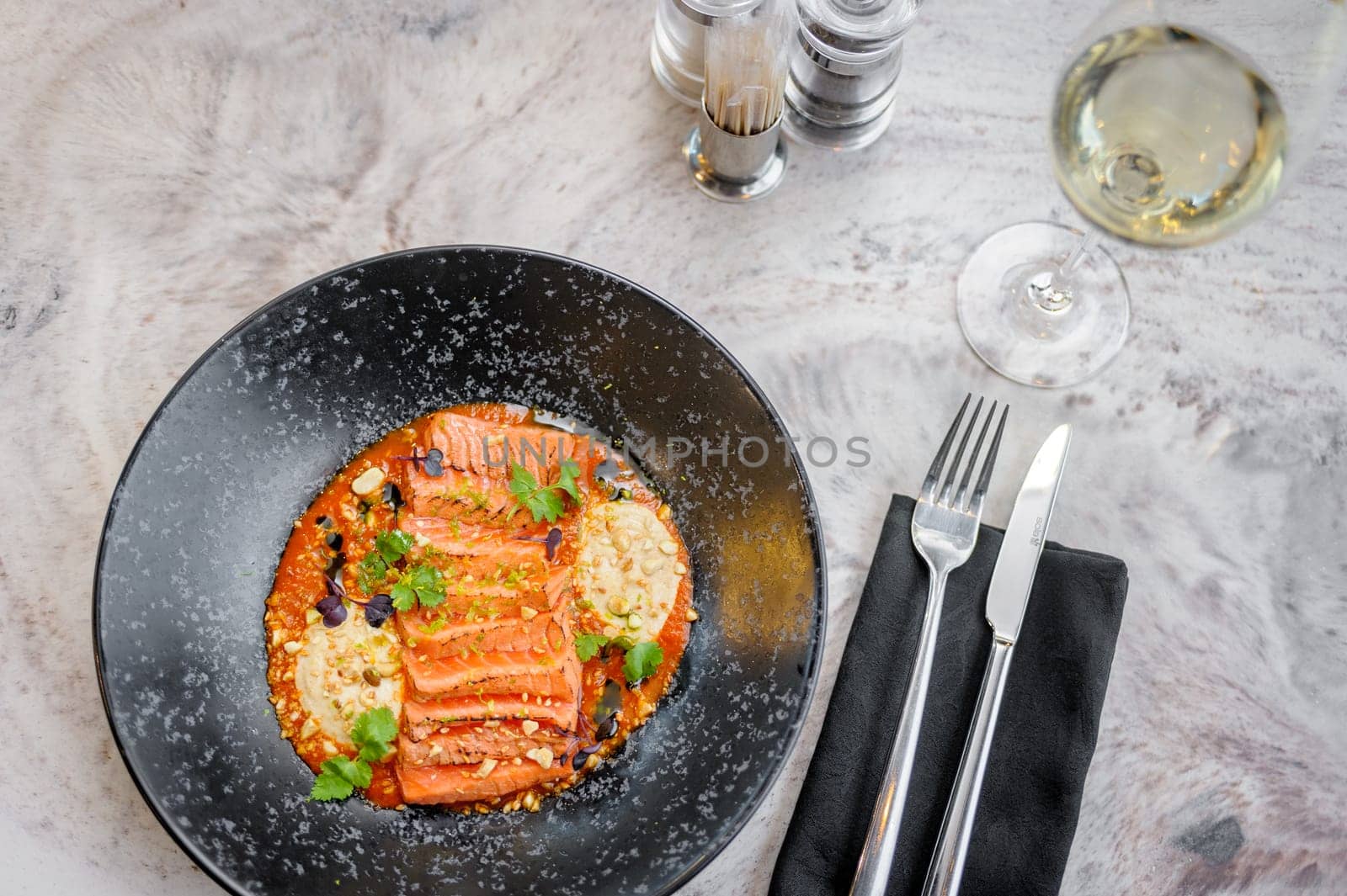 Salmon tataki in sauce with peanuts and herbs on a marble table in a restaurant. High quality photo