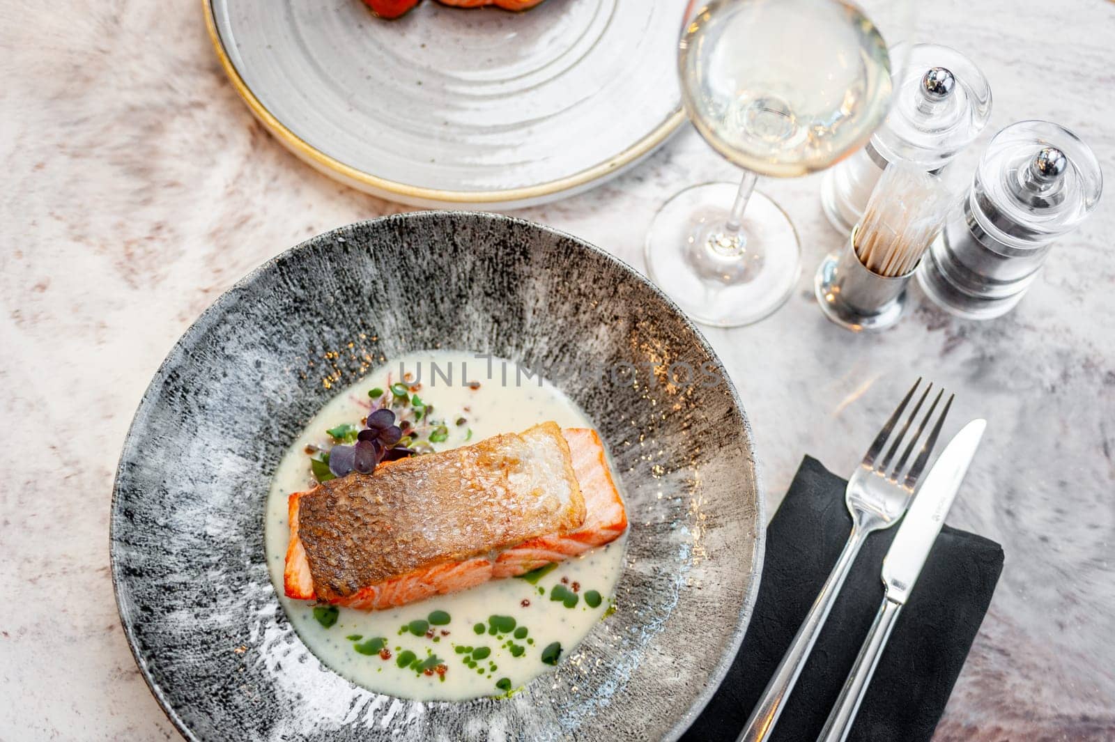 Salmon fillet in cream sauce with herbs on a marble table in a restaurant. High quality photo