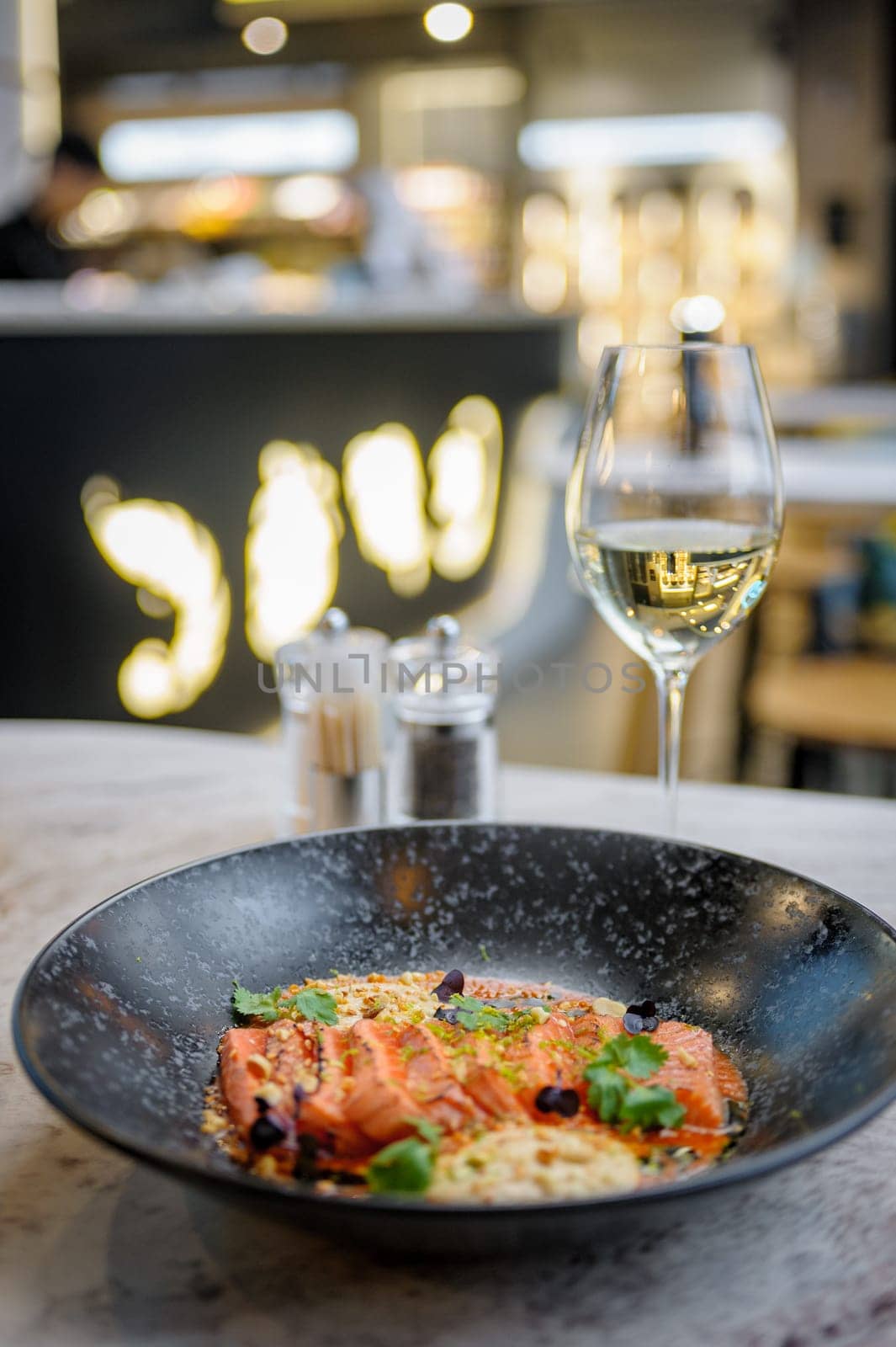 Salmon tataki in sauce with peanuts and herbs on a marble table in a restaurant. High quality photo