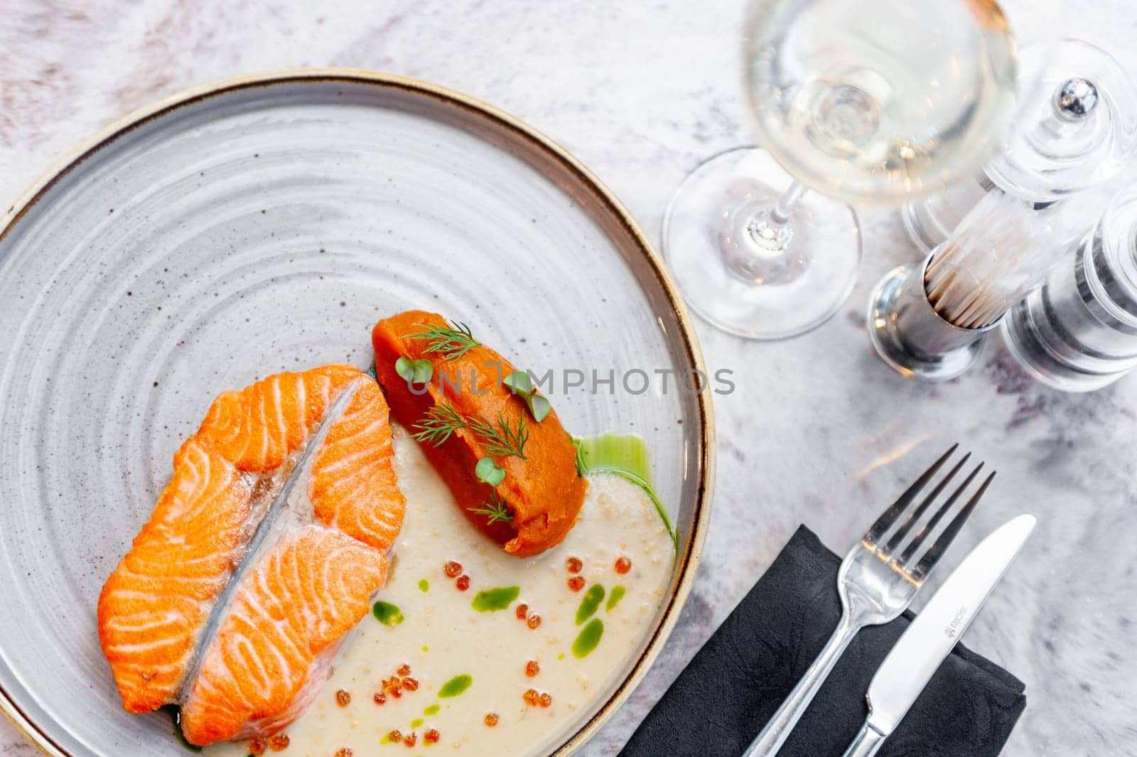Salmon fillet in cream sauce with herbs on a marble table in a restaurant. High quality photo