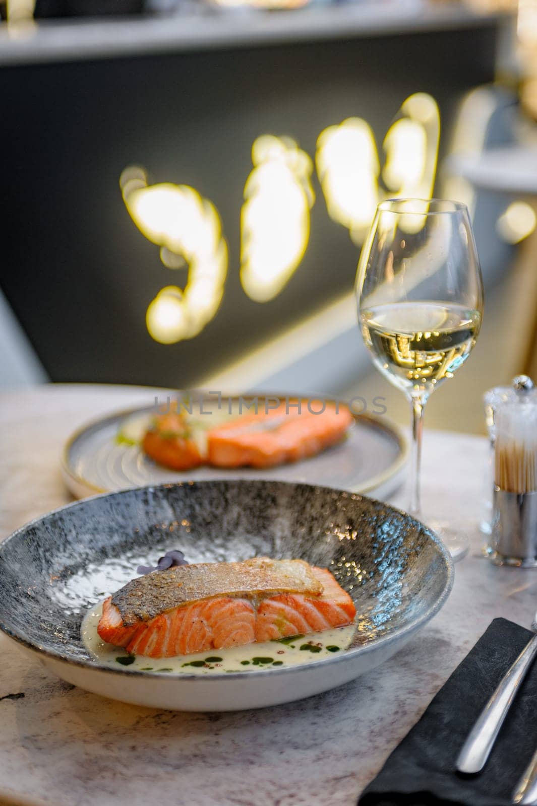 Salmon fillet in cream sauce with herbs on a marble table in a restaurant. High quality photo