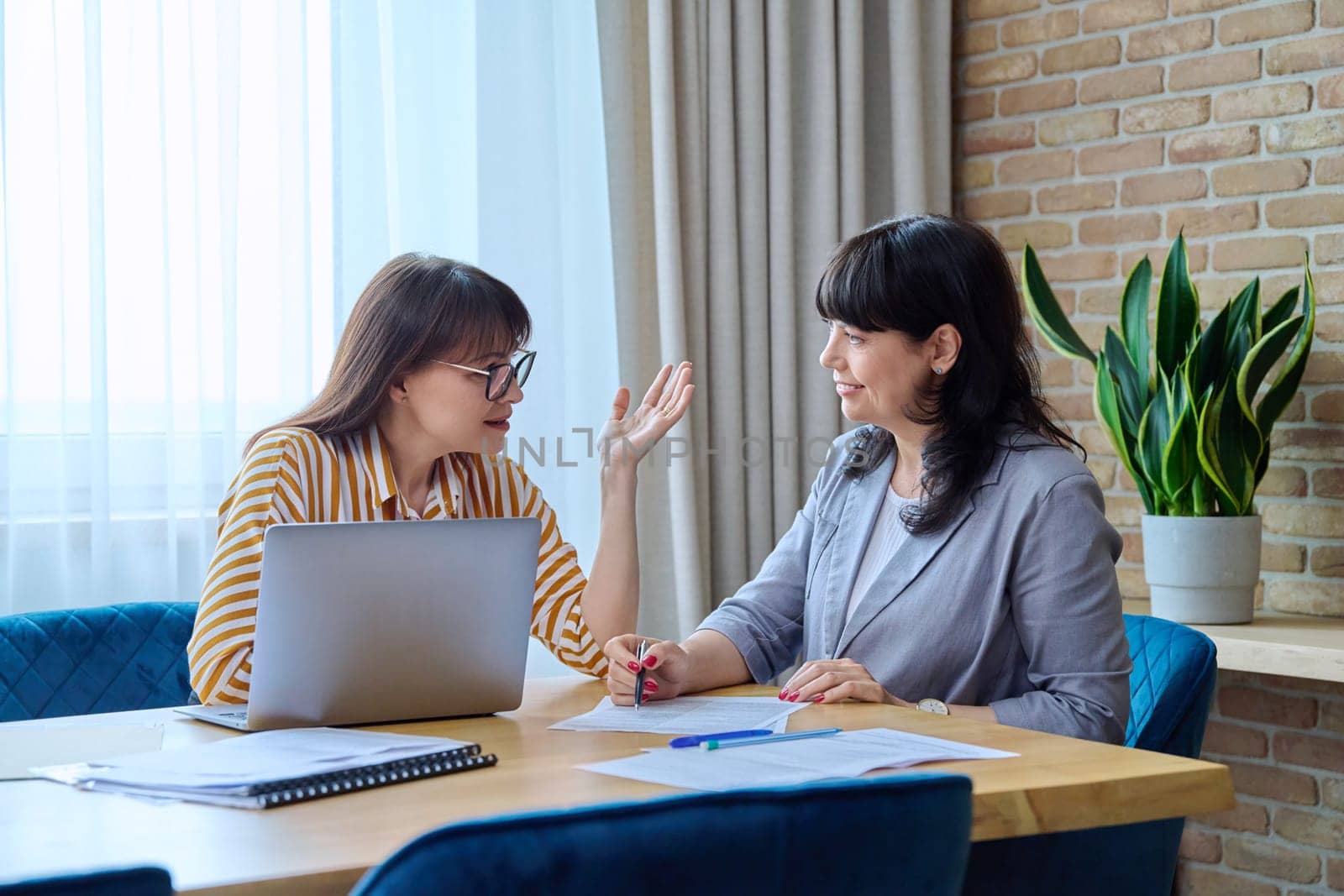 Two mature business women colleagues employees working together in office, middle-aged females preparing contract financial legal plan. Work professionals teamwork communication 40s 50s people on job