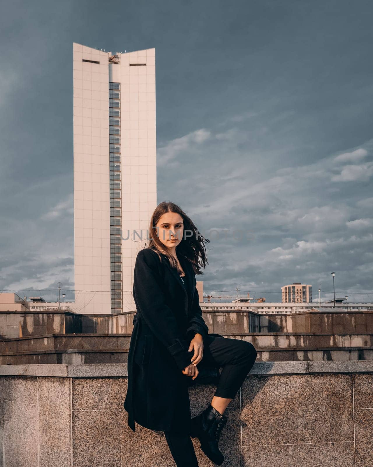 A beautiful girl posing in a city park against the backdrop of a tall building