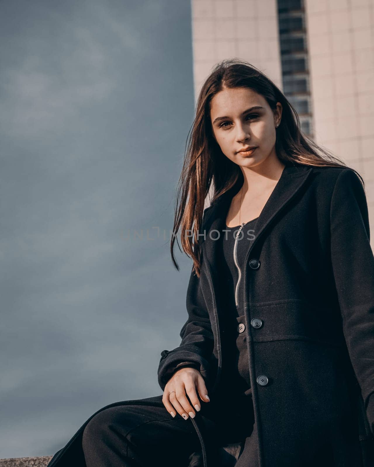 A beautiful girl posing in a city park against the backdrop of a tall building