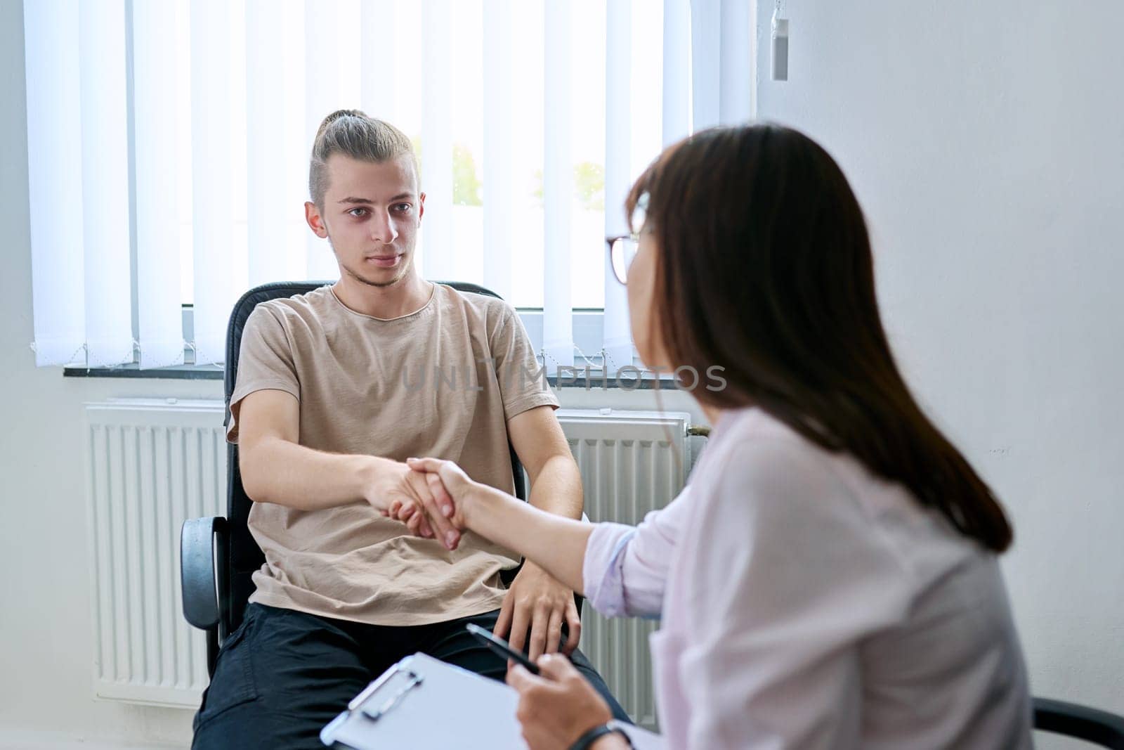 Young male student at therapy meeting with college psychologist counselor. Guy talking to therapist discussing mental social problems with specialist. Psychology, psychotherapy, professional support