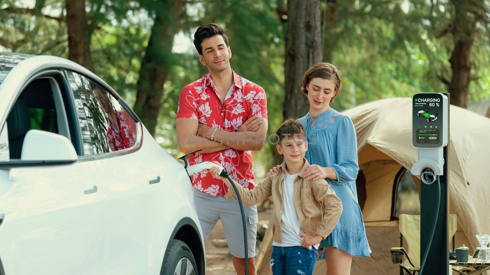 Outdoor adventure and family vacation camping in nature travel by eco friendly car for sustainable future. Lovely family recharge EV car with EV charging station in campsite. Perpetual