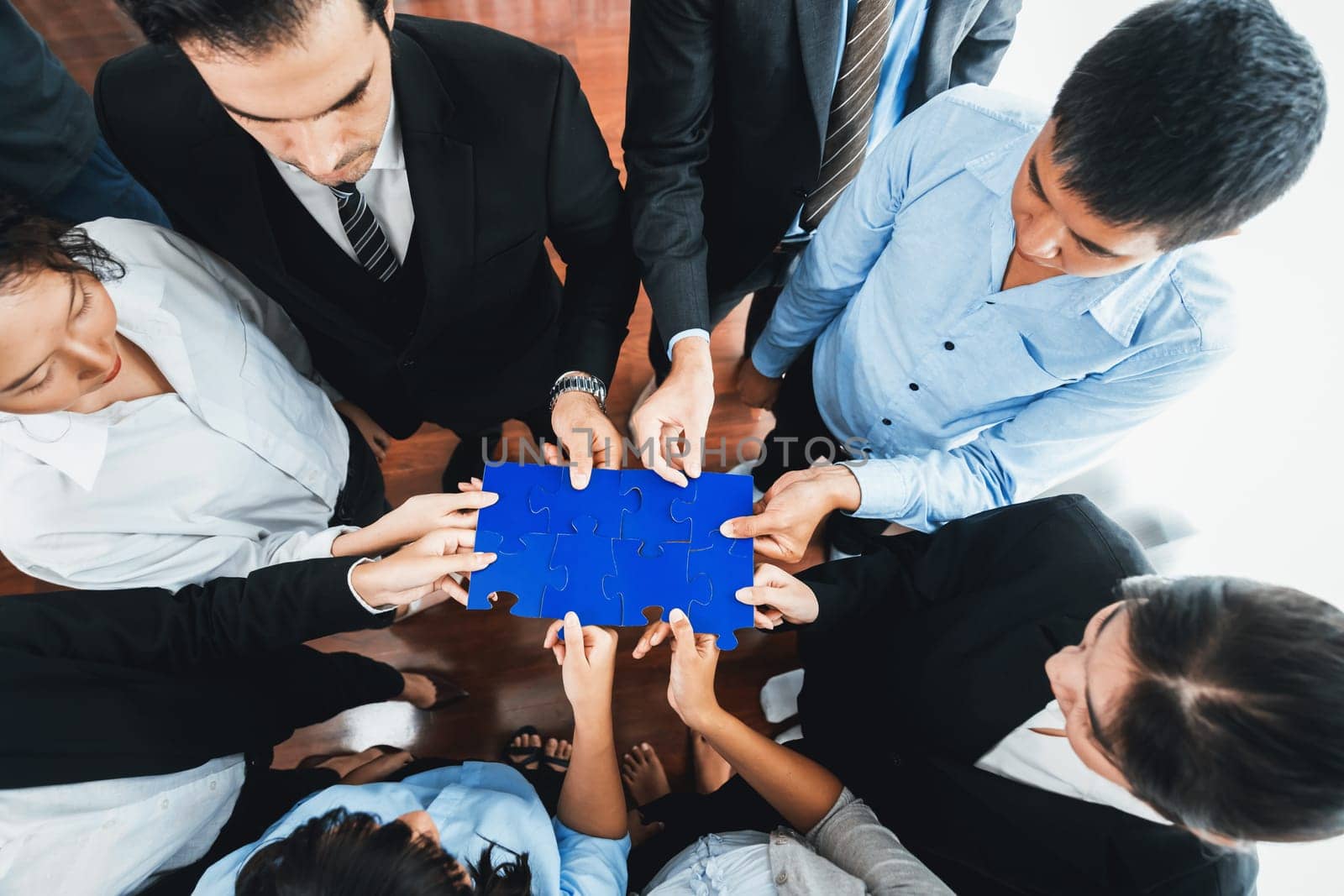 Top view multiethnic business people holding jigsaw pieces and merge them together as effective solution solving teamwork, shared vision and common goal combining diverse talent. Meticulous