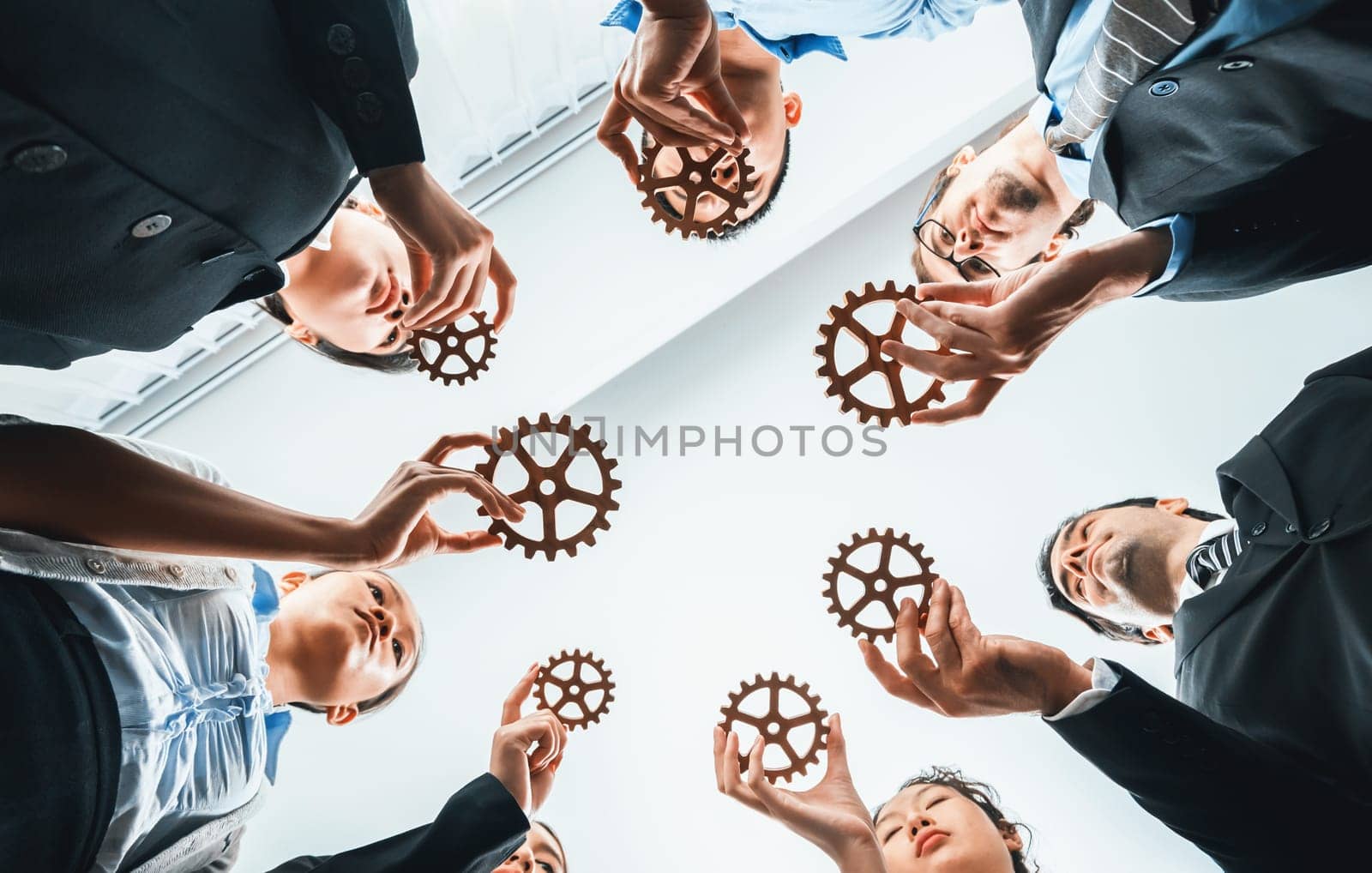 Below view group of multiracial business people joining gear wheels together as effective unity and productive teamwork concept. Efficient system business team process for solution solving. Habiliment