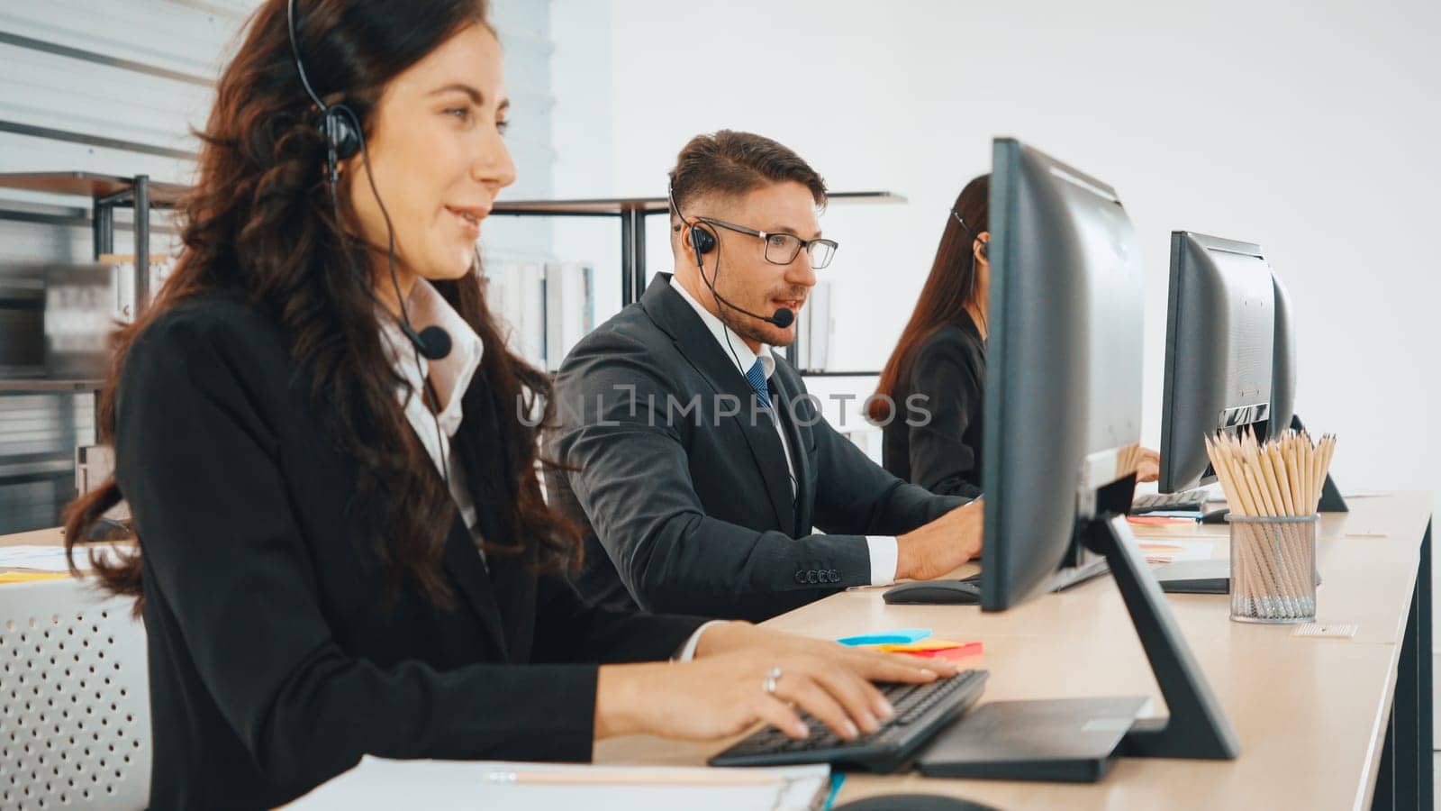 Business people wearing headset working in office to support remote customer or colleague. Call center, telemarketing, customer support agent provide service on telephone video conference call. Jivy