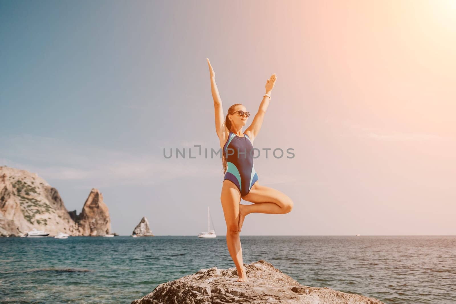 Woman sea yoga. Back view of free calm happy satisfied woman with long hair standing on top rock with yoga position against of sky by the sea. Healthy lifestyle outdoors in nature, fitness concept.