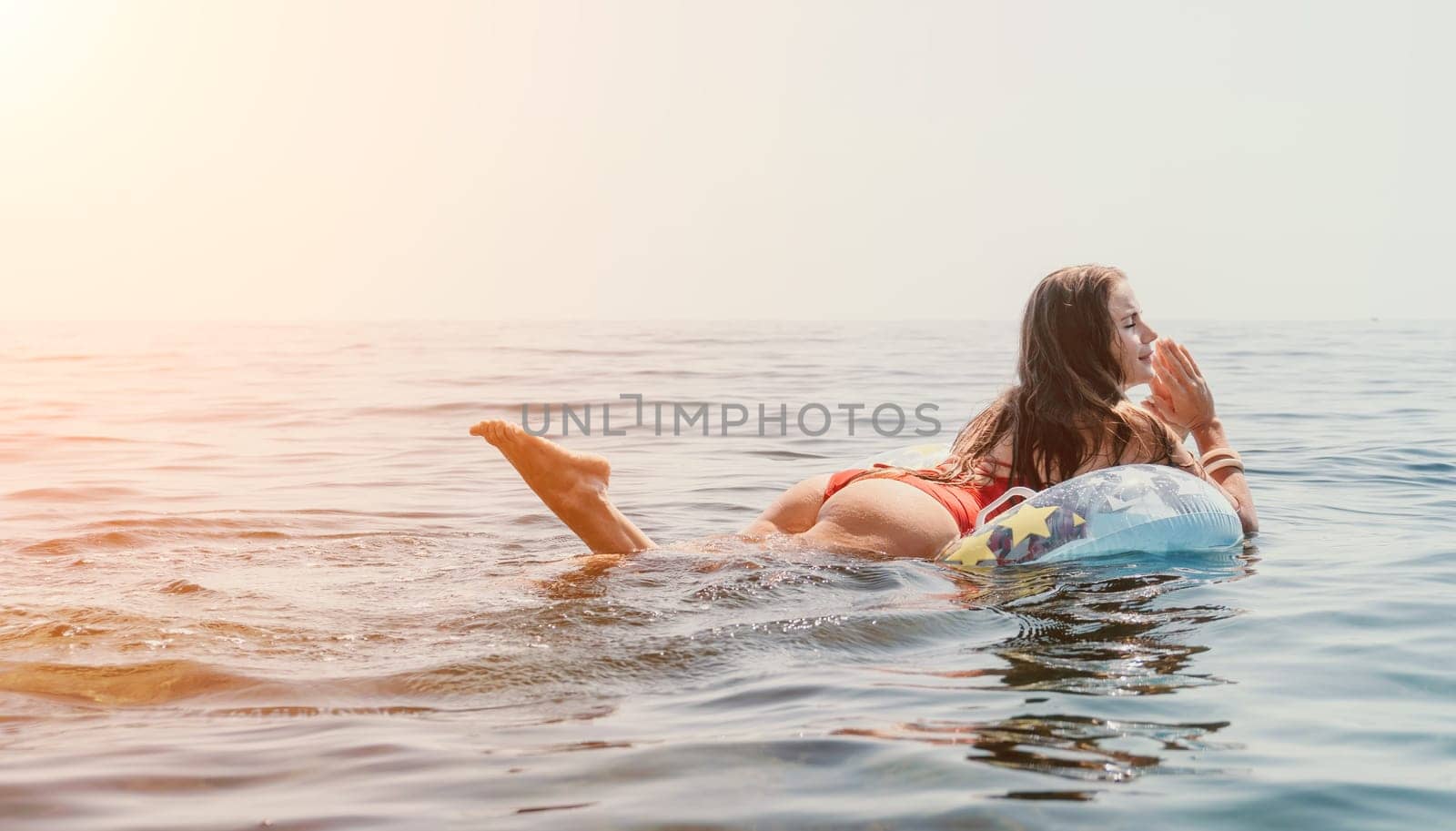 Woman summer sea. Happy woman swimming with inflatable donut on the beach in summer sunny day, surrounded by volcanic mountains. Summer vacation concept