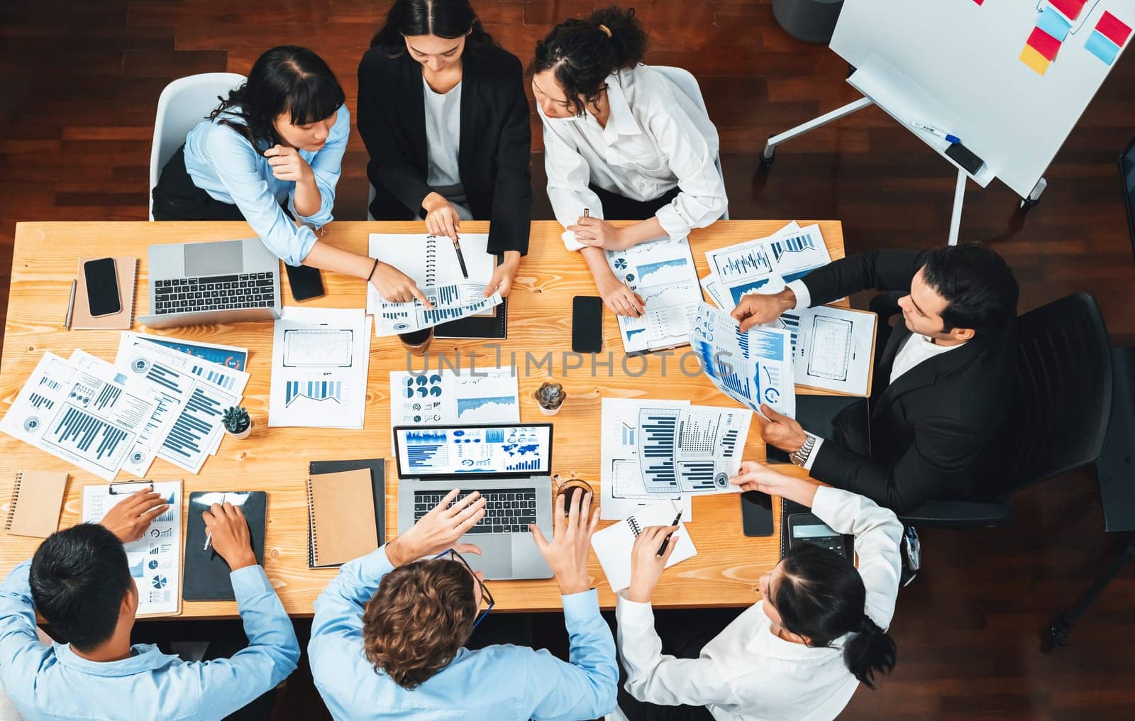 Panorama top view diverse group of business analyst team analyzing financial data report paper on meeting table. Chart and graph dashboard by business intelligence analysis. Meticulous