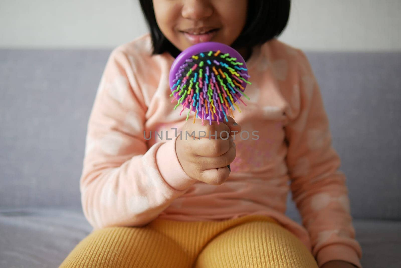 child hand holding a colorful hair brush at home