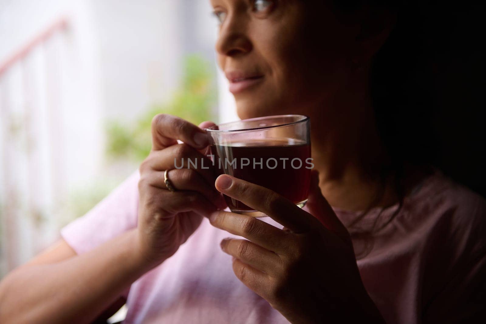 Woman gazing thoughtfully while sipping tea, capturing a serene and reflective moment indoors.