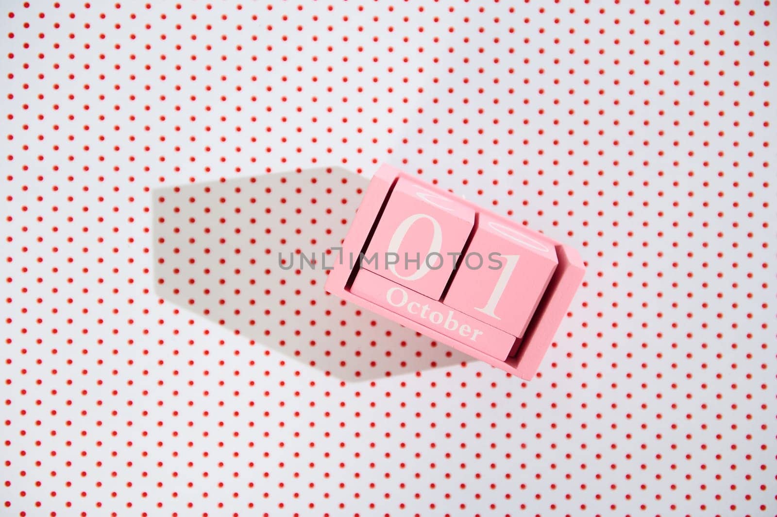A pink block calendar displaying October 1st on a white polka dot background, creating a playful and modern aesthetic. Ideal for autumn or event imagery.