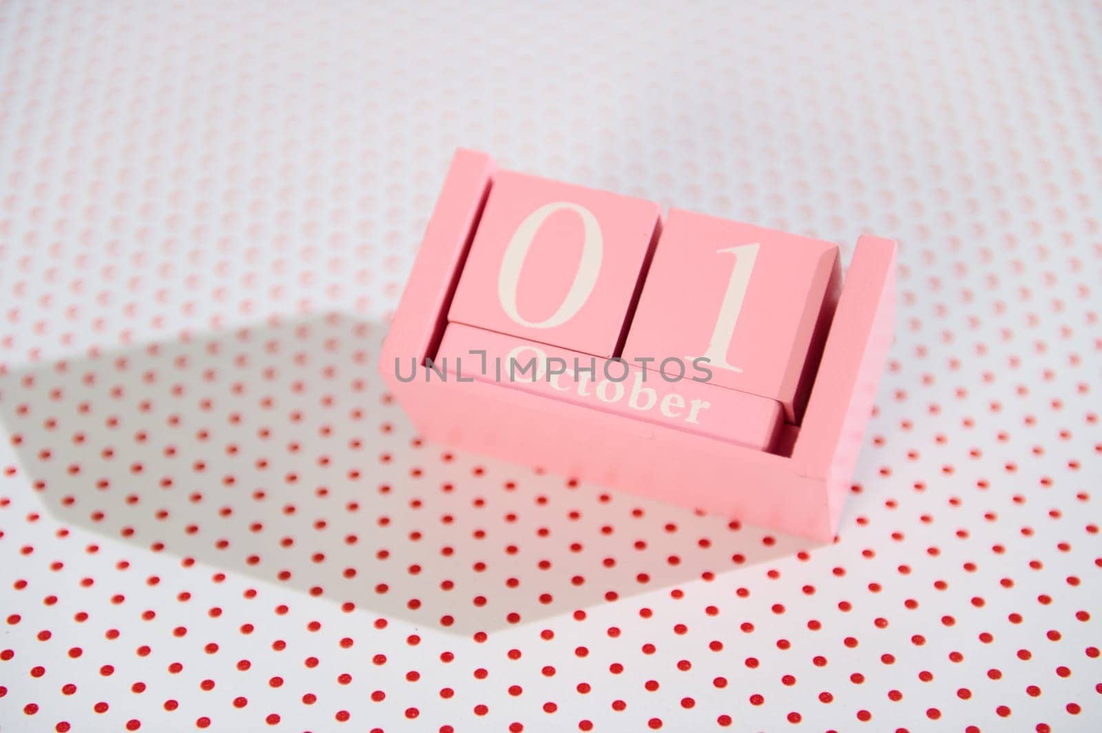 Pink wooden calendar block showing October 1st on a dotted background, ideal for autumn and event reminders.