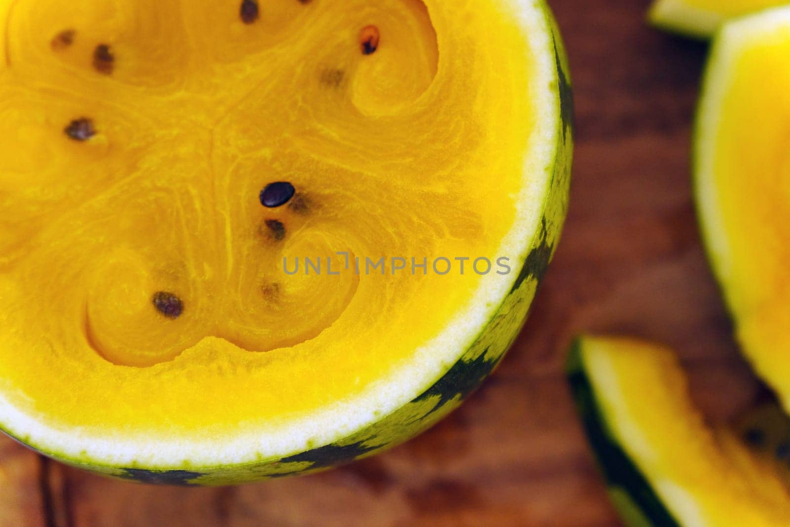 Slices of vibrant yellow watermelon are artistically displayed on a rustic wooden cutting board