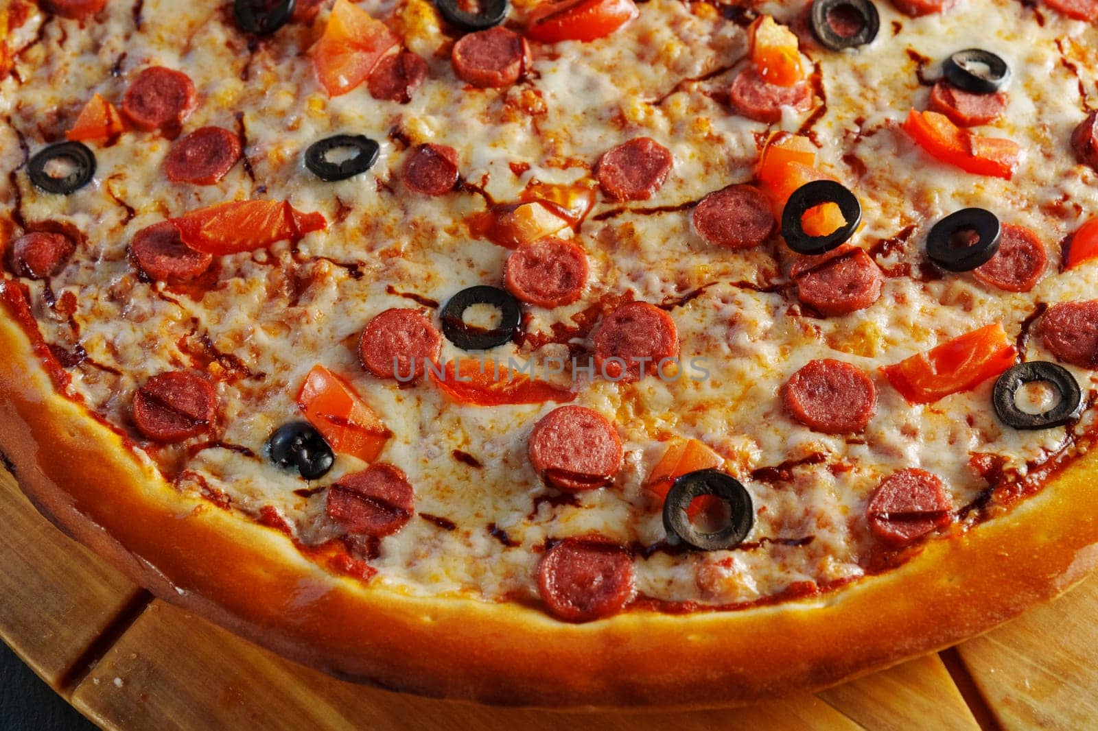 Delight in a mouthwatering pizza adorned with pepperoni slices and black olives, fresh tomato pieces, and a rich swirl of sauce, perfect for any occasion.