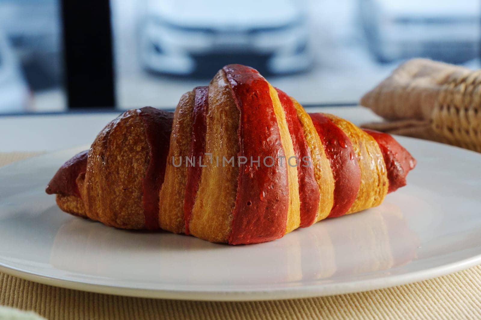 Golden brown croissant sits invitingly on a plate beside a textured linen napkin in a cozy setting