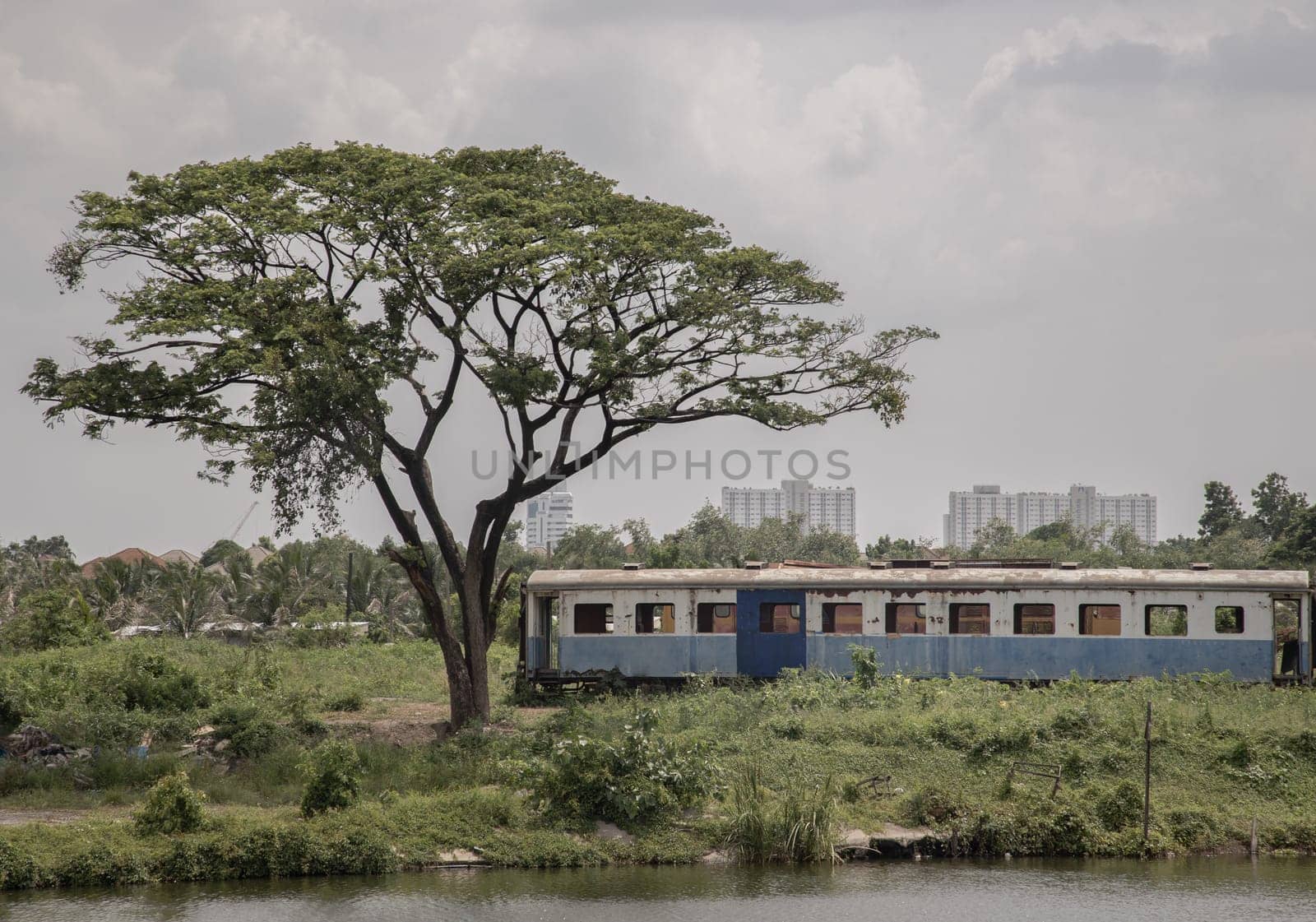Bangkok, Thailand - May 28,2022 - View of vintage railroad container is parked in wasteland and swamp with sky background. The empty old rusty passenger train and abandoned, Space for text, Selective focus.