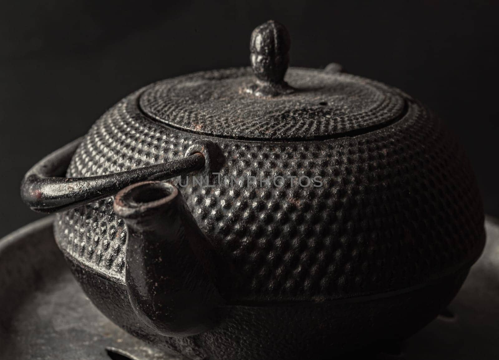 Bangkok, Thailand - 17 Sep, 2024 - Close-up of Black cast iron kettle or teapot on dark background. Light and Shadow, Space for text, Selective Focus.